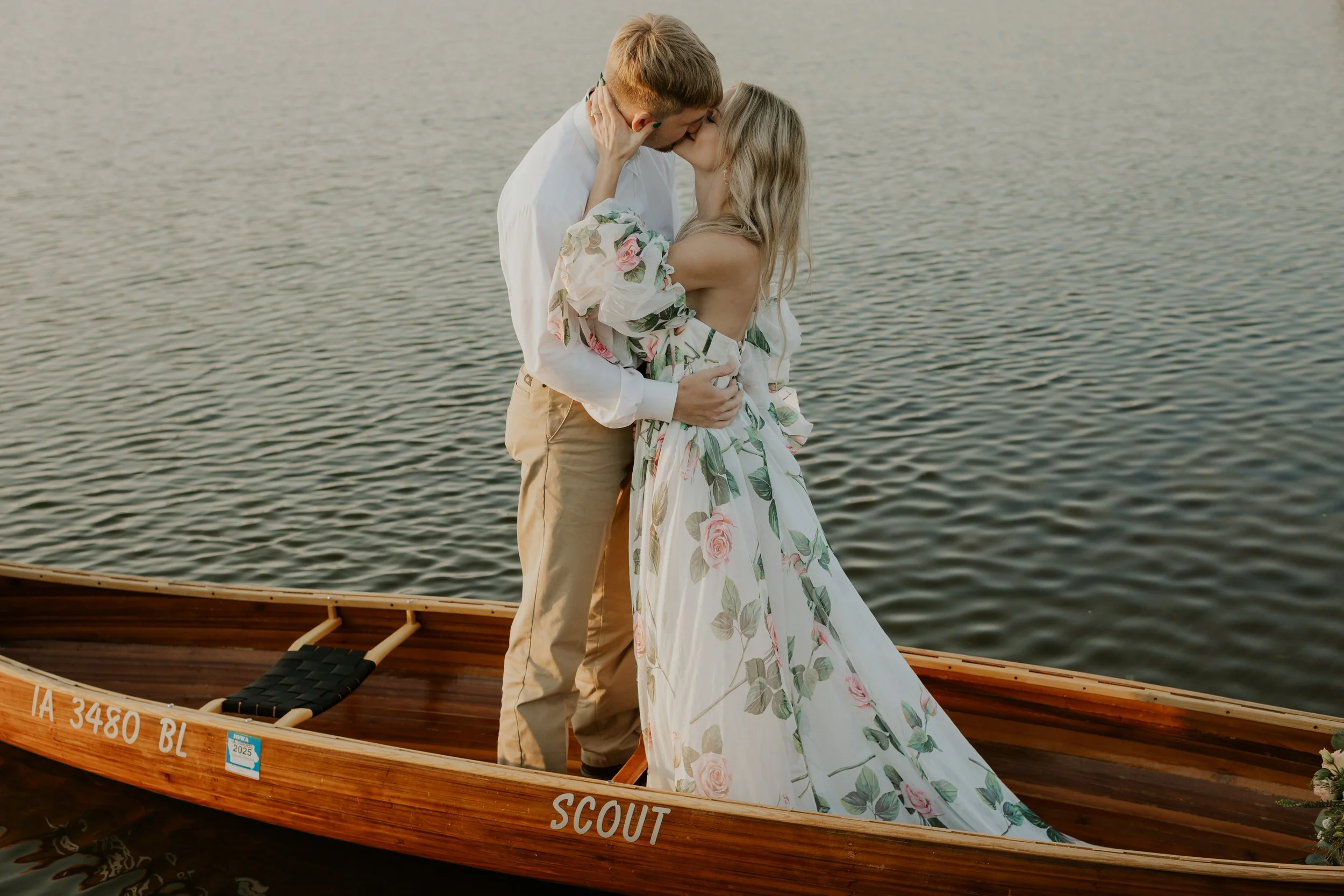 bridal couple standing up and kissing in canoe on lake