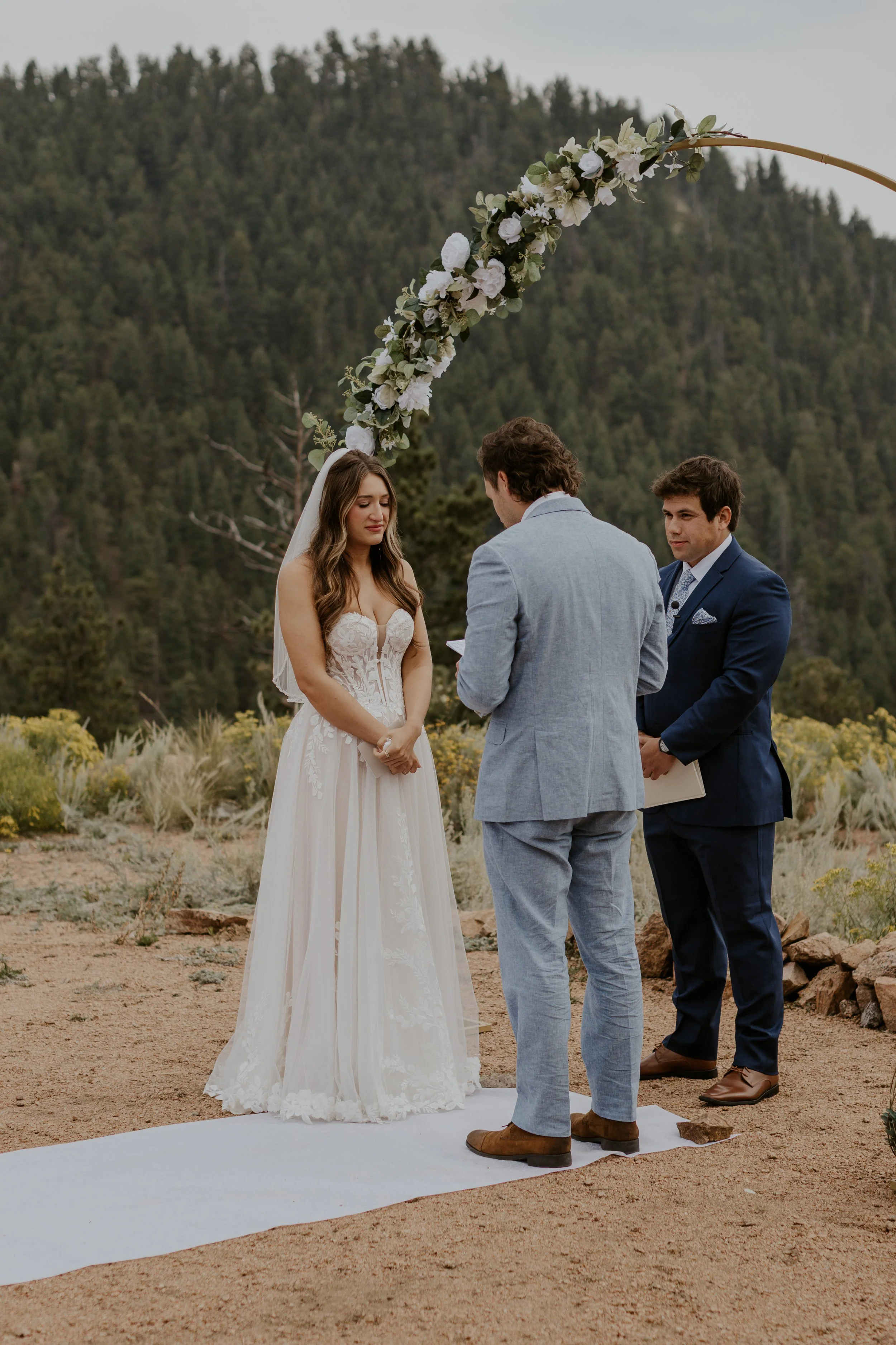 groom reading vows during mountain top ceremony while bride smiles and cries