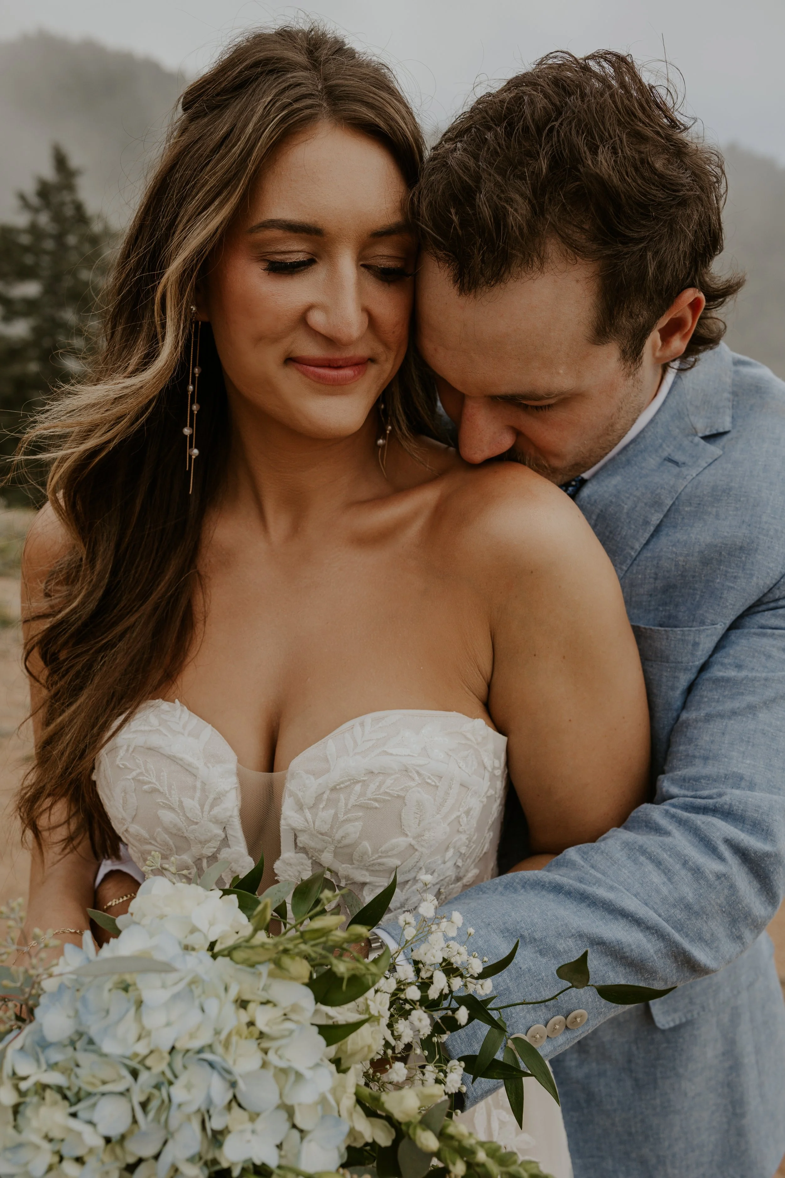 groom embracing bride from behind as they snuggle up together in colorado