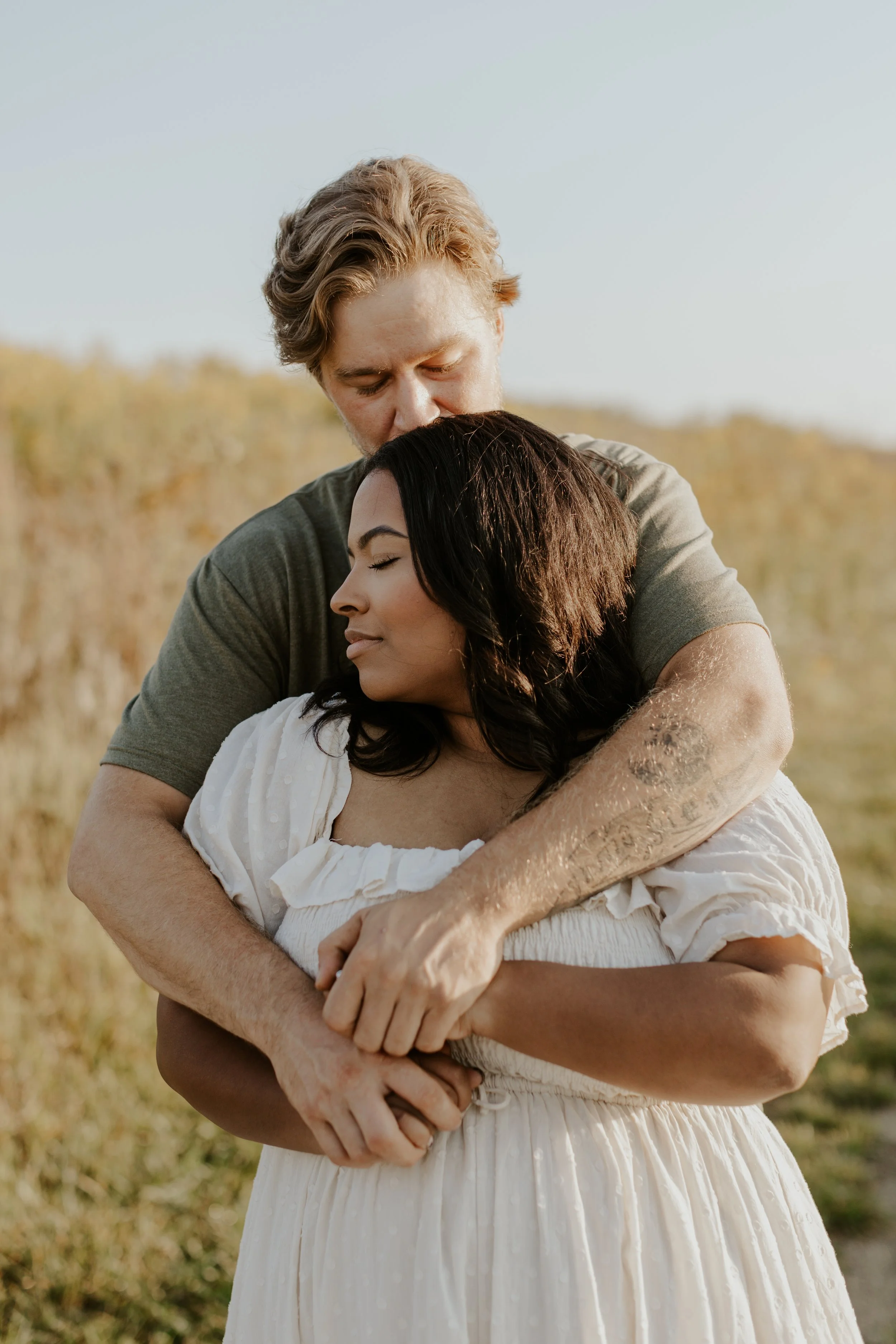 intimate moment of young engaged couple embracing in field