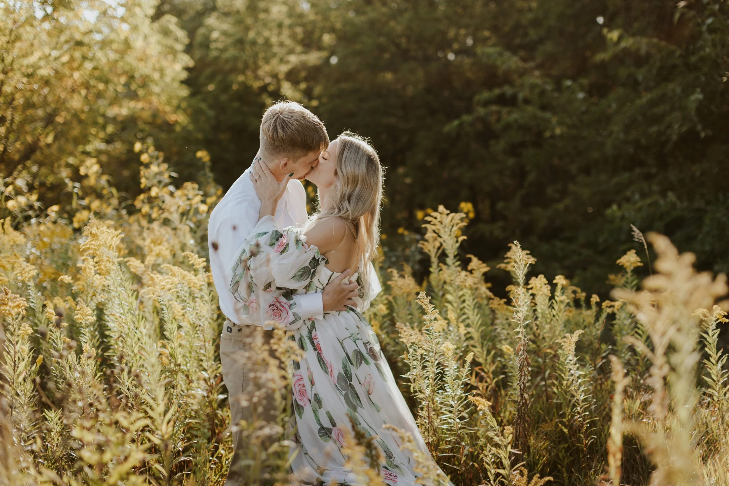 Eloping couple in bridal attire embracing and kissing in wisconsin field