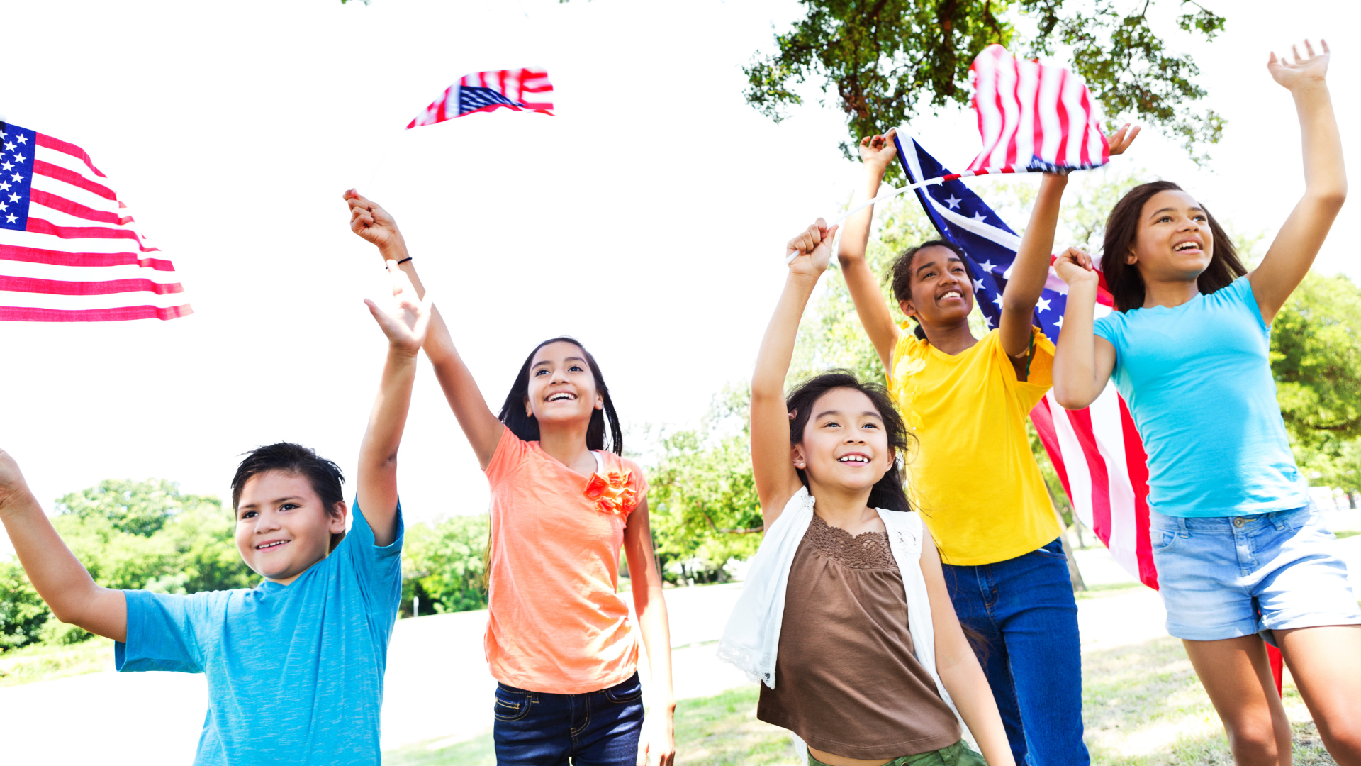 Young smiling children waving American flags outdoors