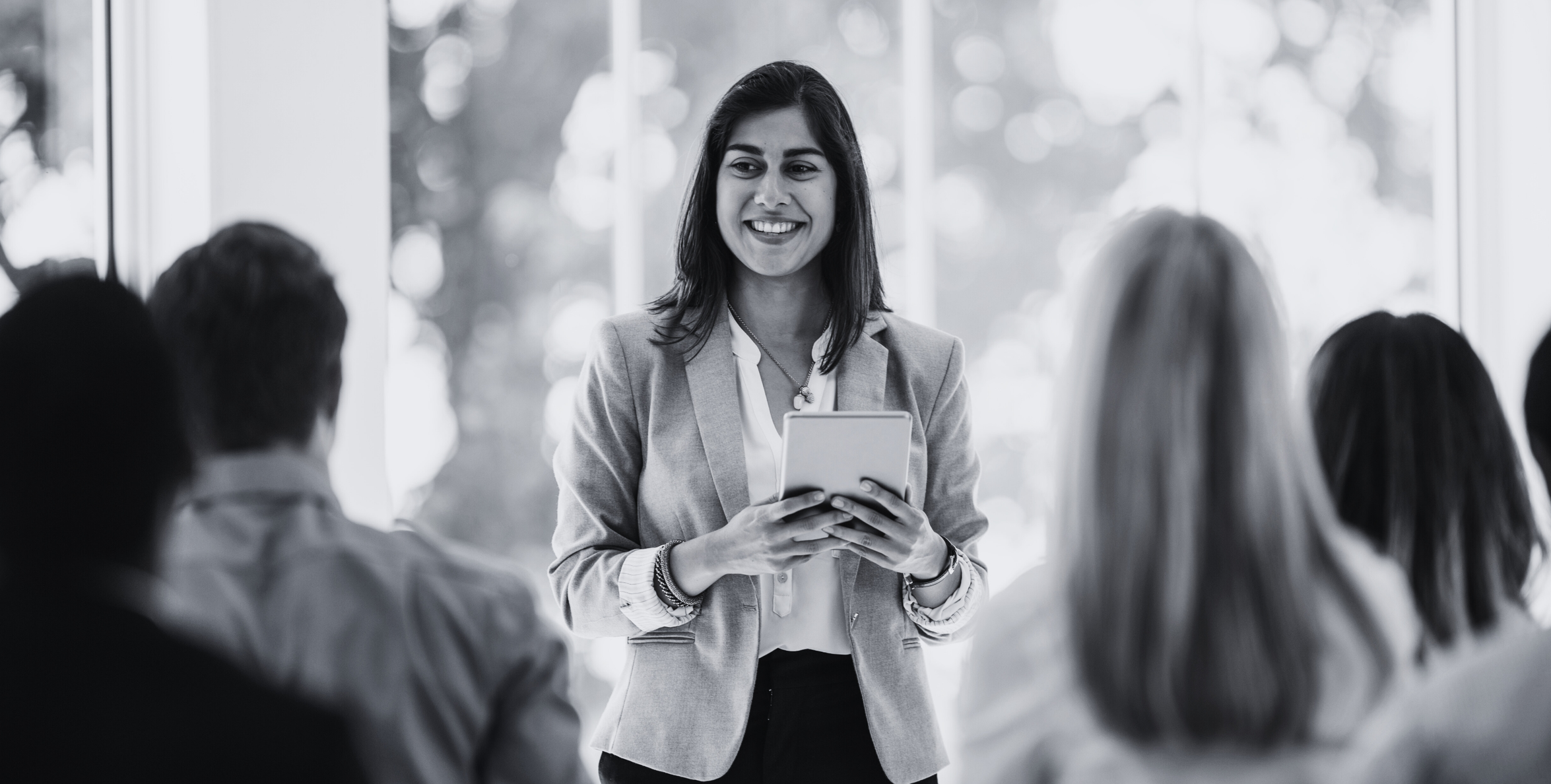 Woman standing in front of audience with tablet