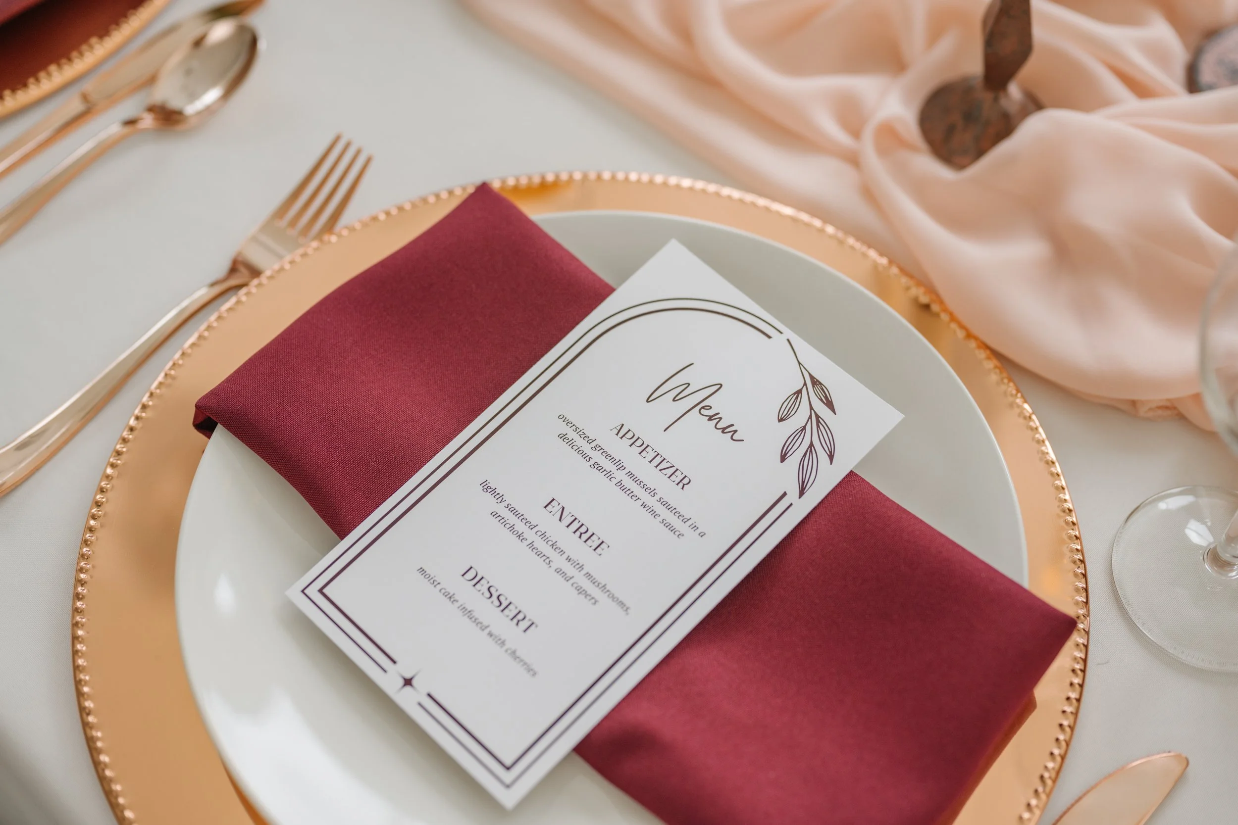 Wedding menu set on burgundy napkin with copper charger plate, designed by Courtney, with Heirloom weddings in Utah