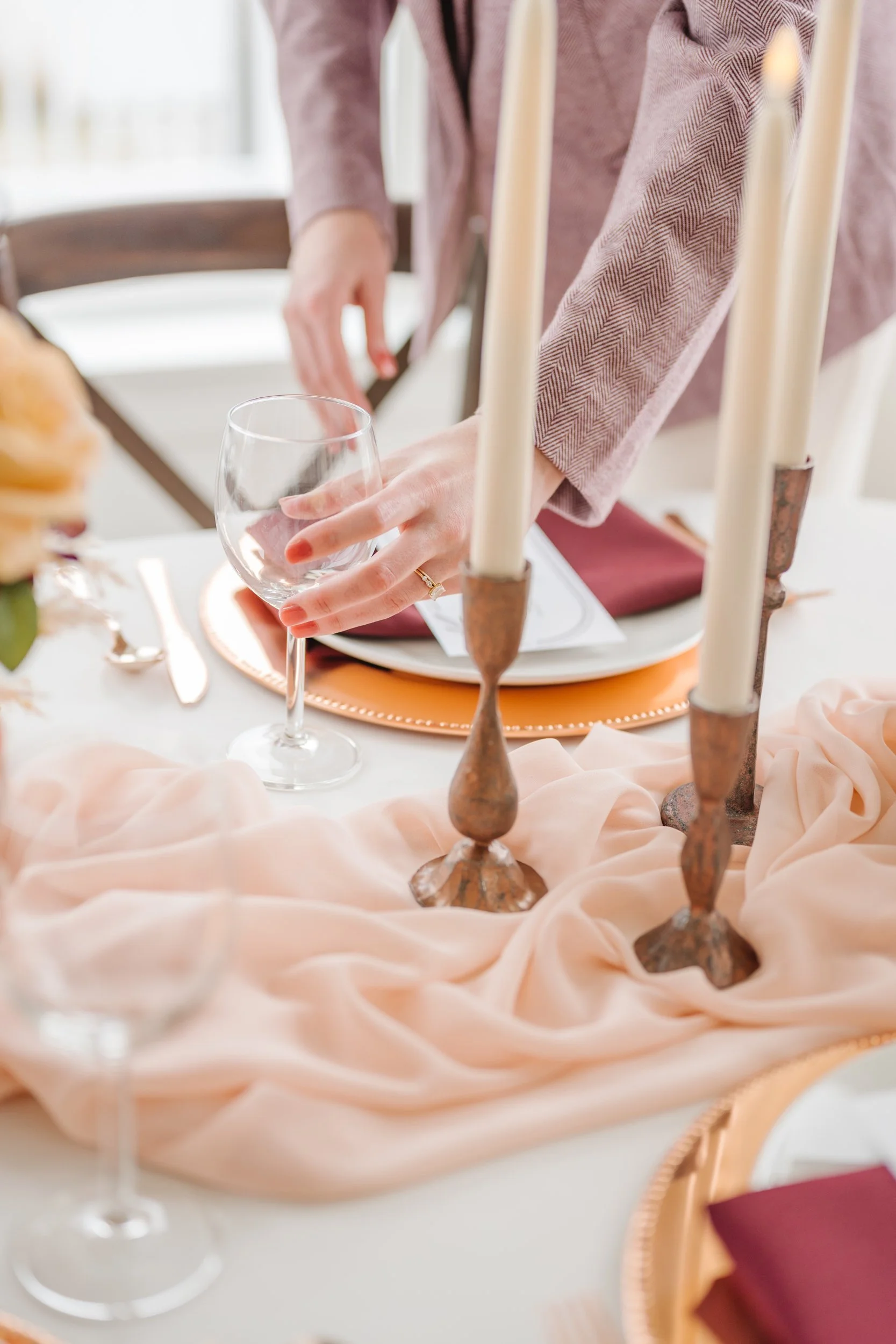 Utah wedding planner setting elegant wedding reception table with burgundy napkins and copper charger plates in Utah.