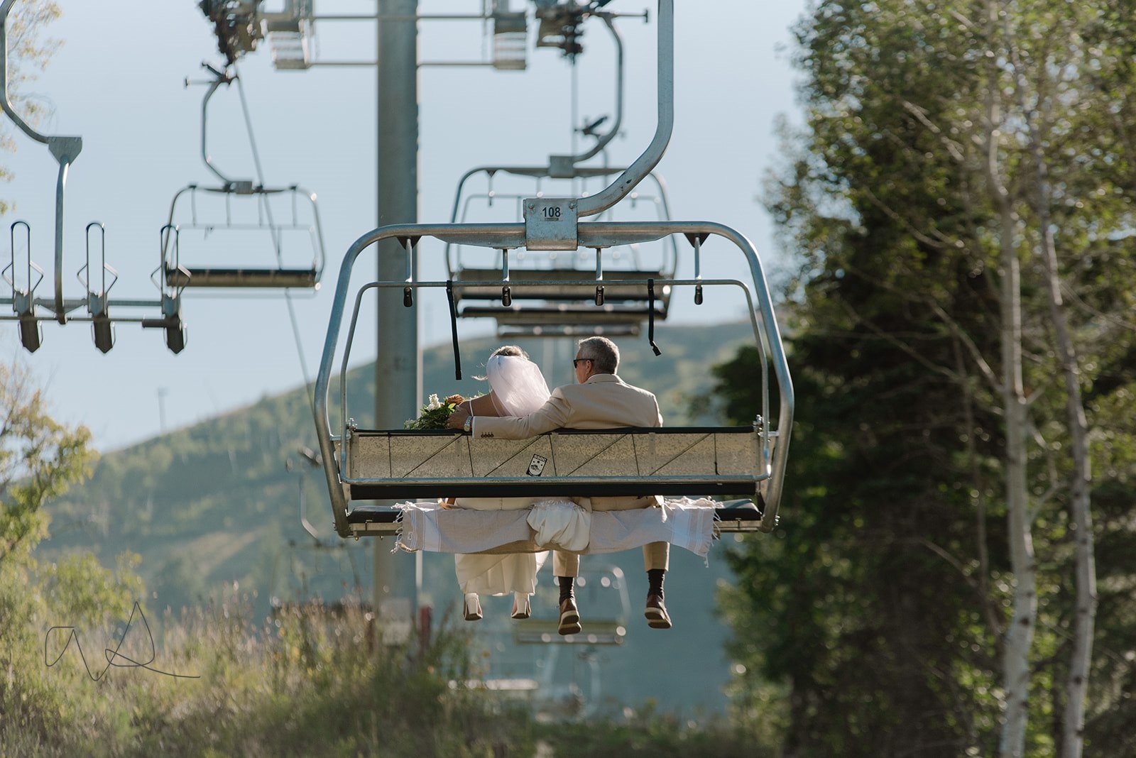 Bride riding the ski lift to the Mandan Summit for her wedding ceremony at Sundance Ski Resort, Utah.