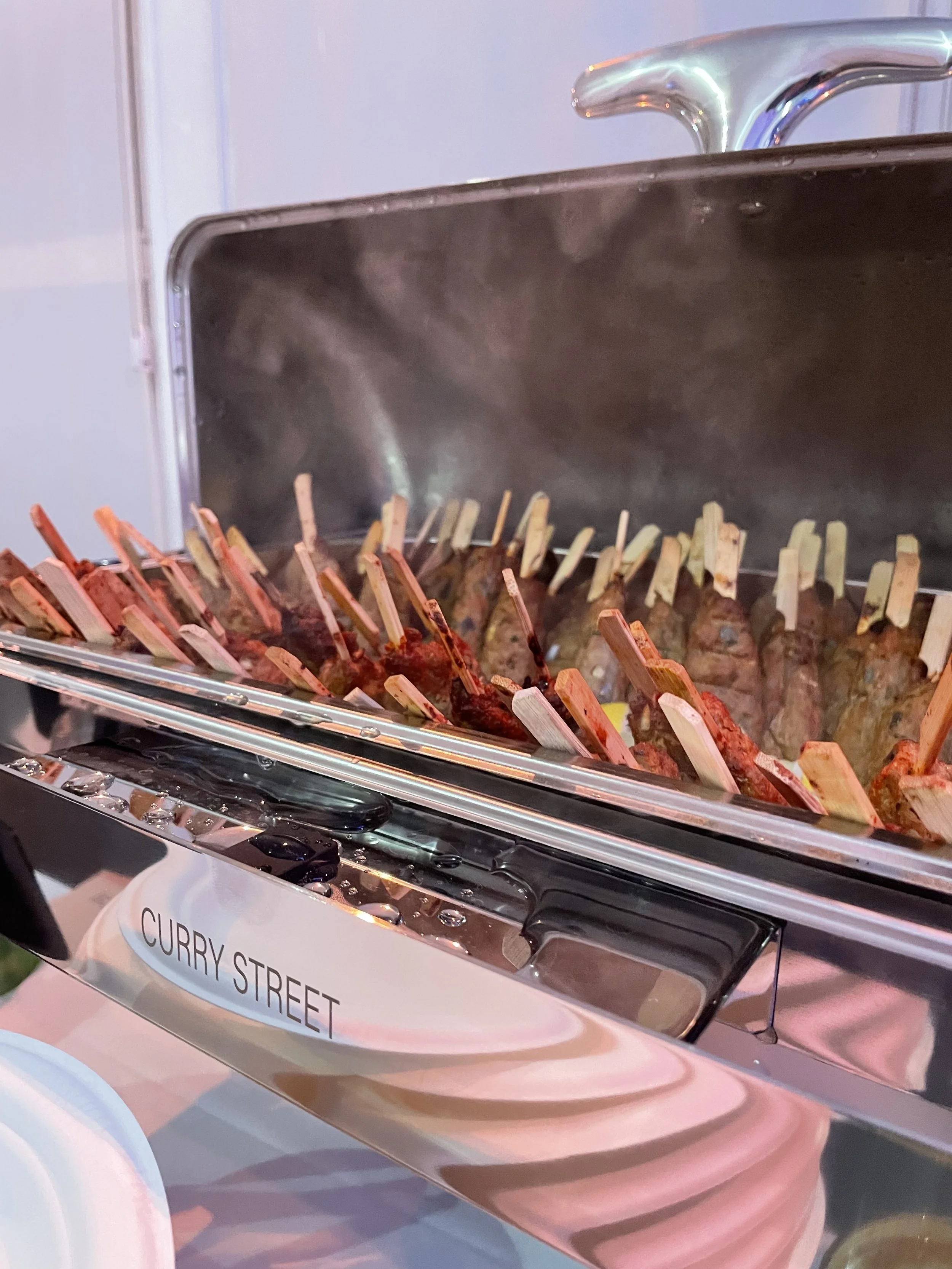 Brochettes de viande dans une marmite de style street food, étiquetée Curry Street.