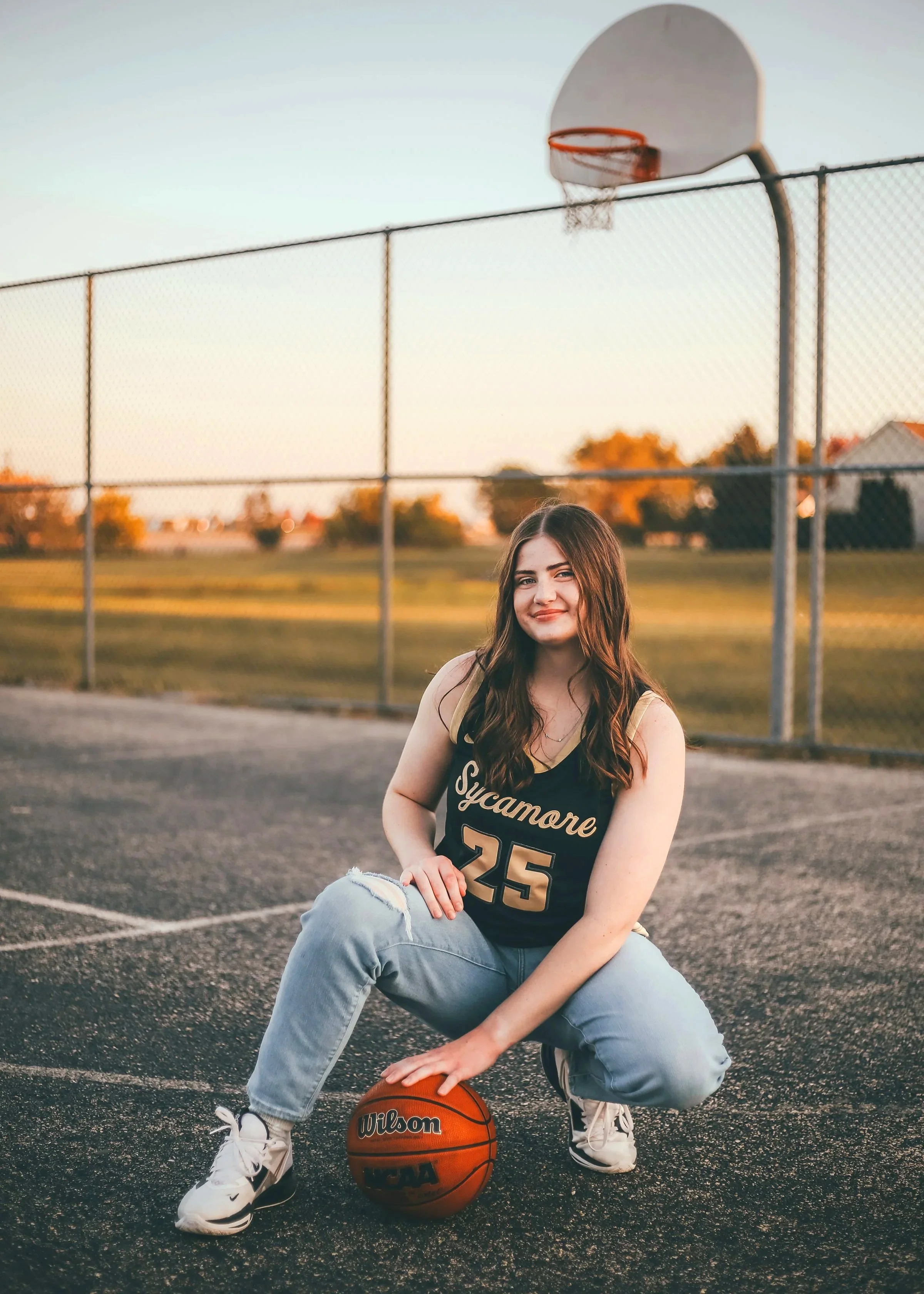Sycamore HS Girl's Basketball Senior Posing with basketball on concrete basketball court