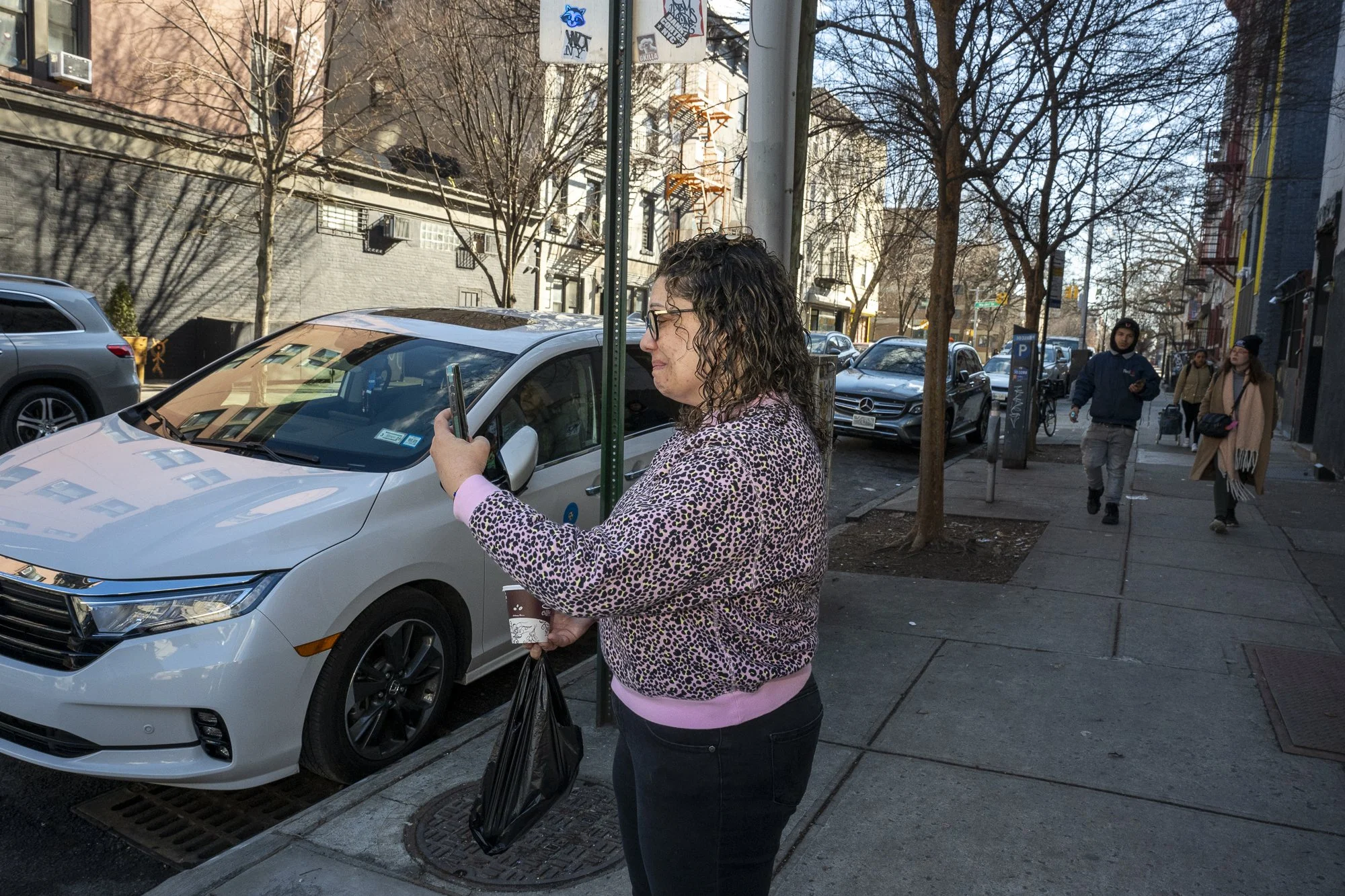 Another woman records Idiotarod teams walking to Bushwick Country Club