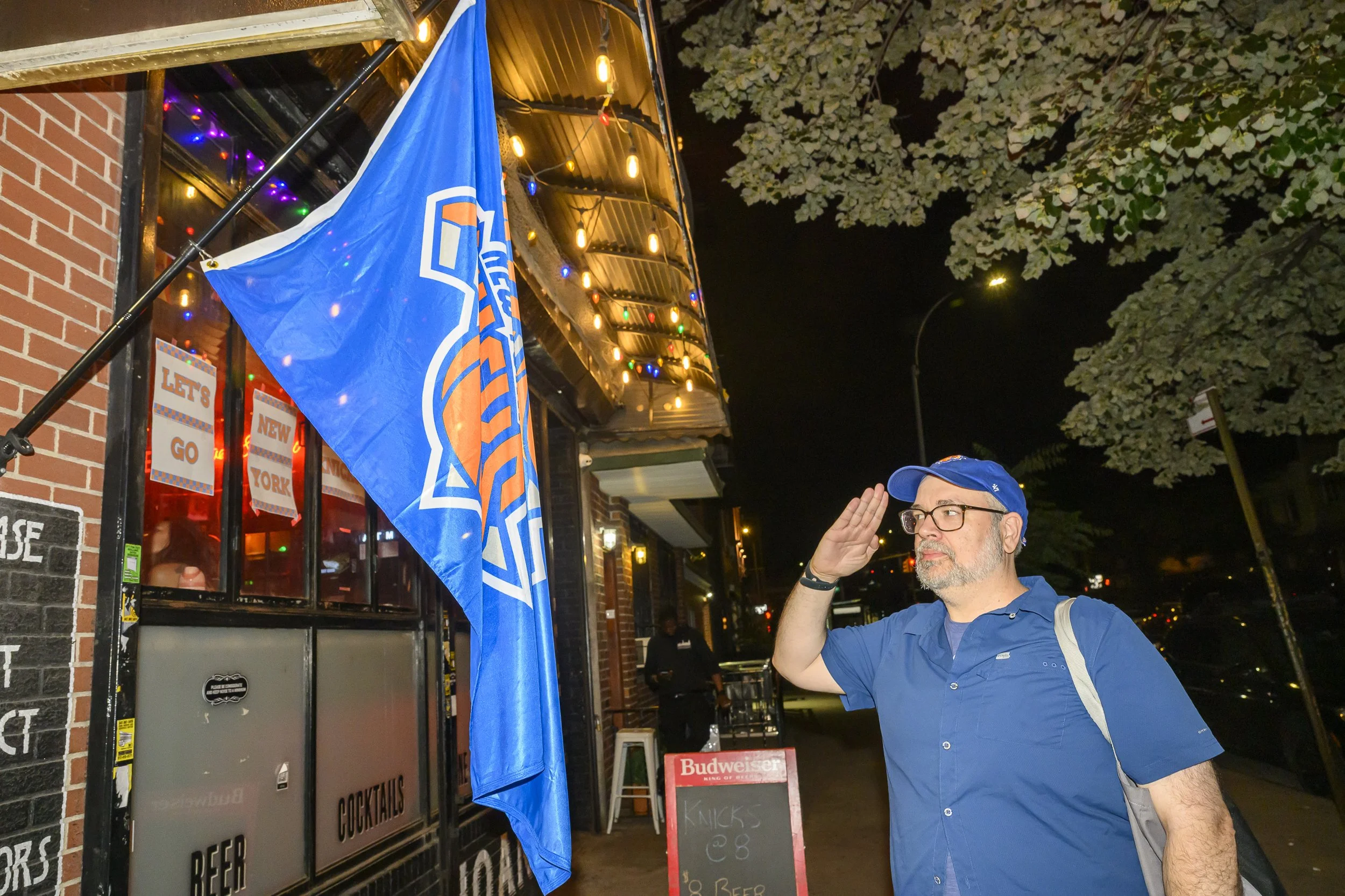 Eric salutes a New York Knicks flag outside a bar on Graham Ave.
