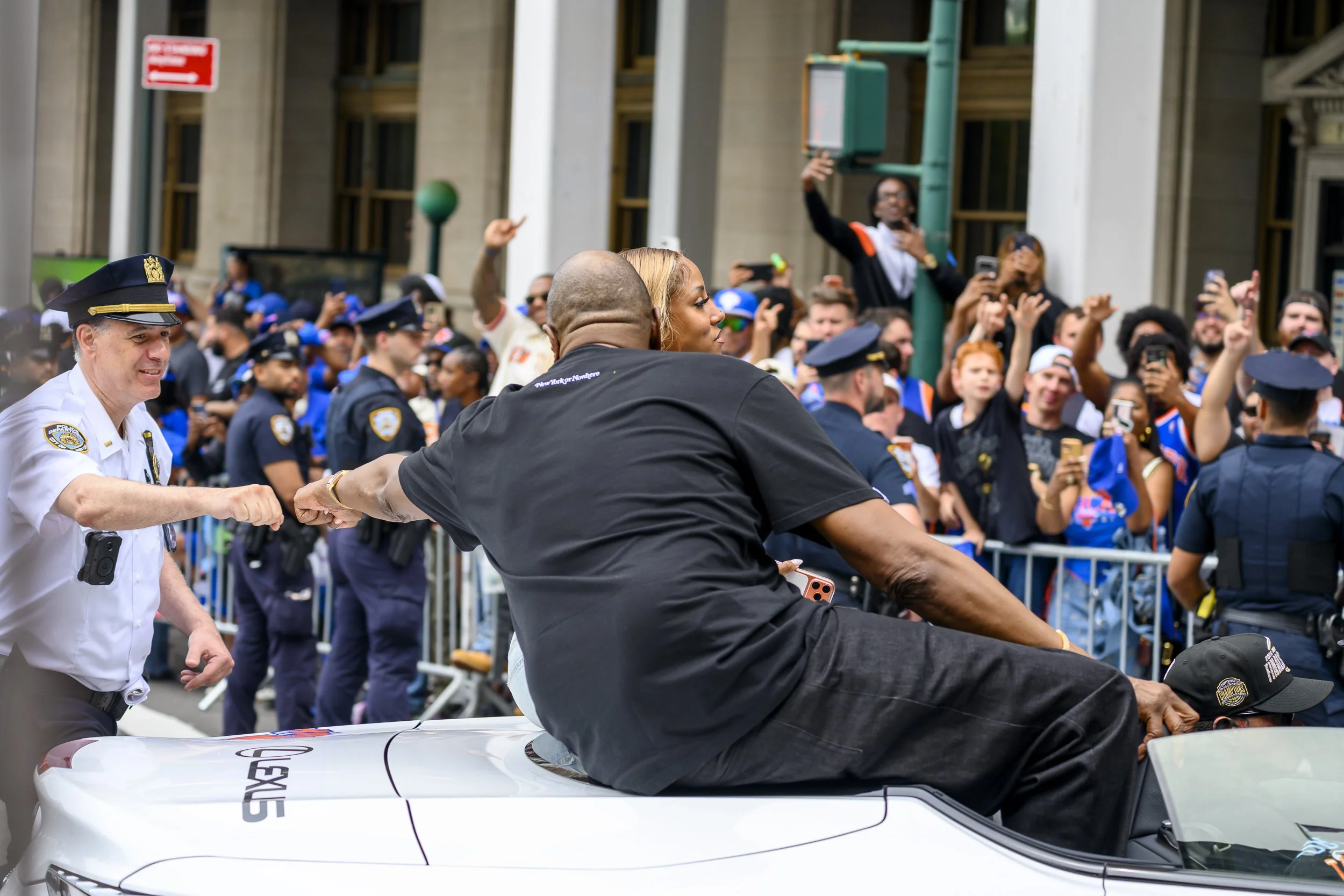 A NYPD officer fist bumps Patrick Ewing at the New York Knicks Championship Parade