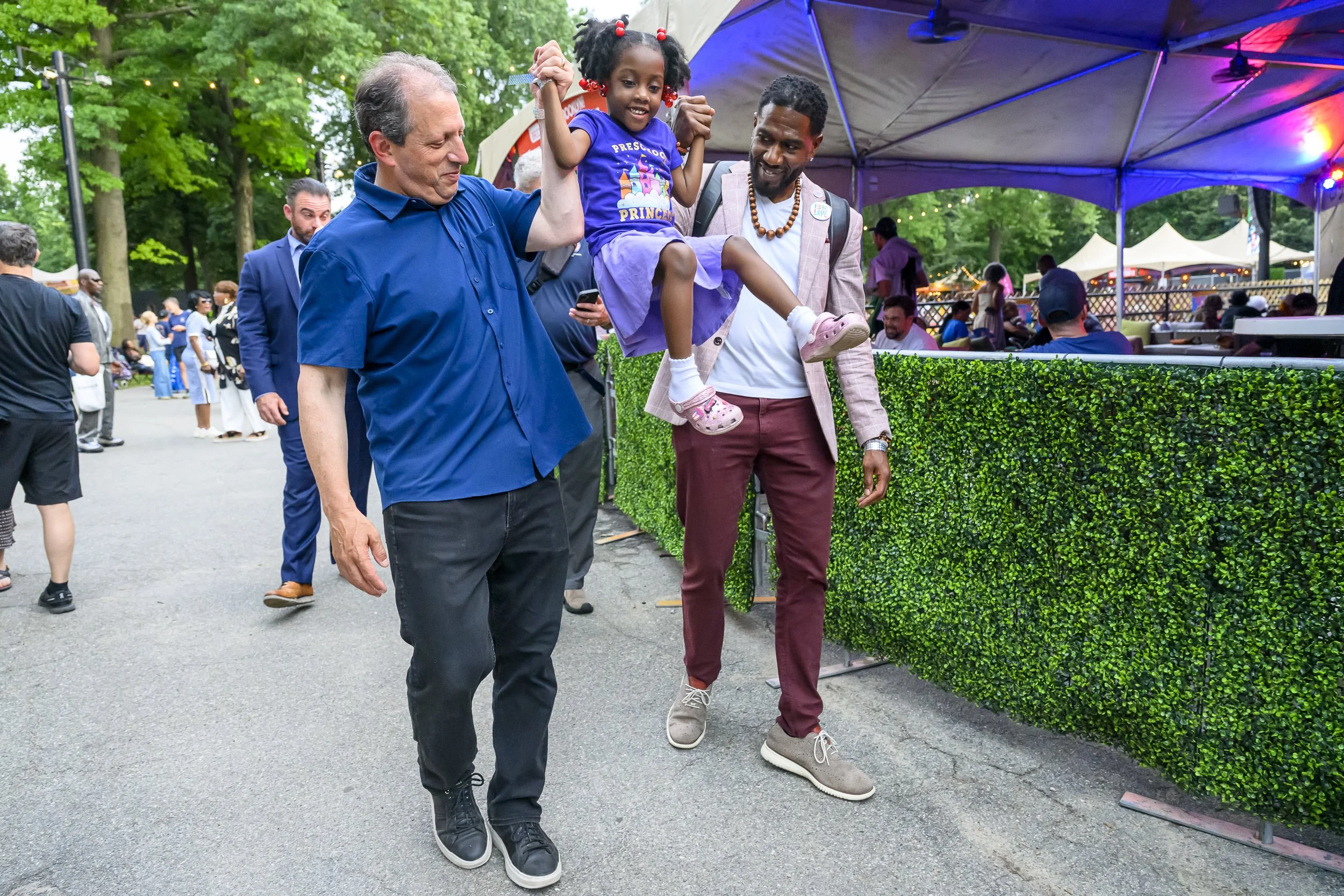 House Representative elect Brad Lander and New York City Public Advocate Jumaane Williams raise Williams' daughter in the air while walking at BRIC Celebrate Brooklyn!