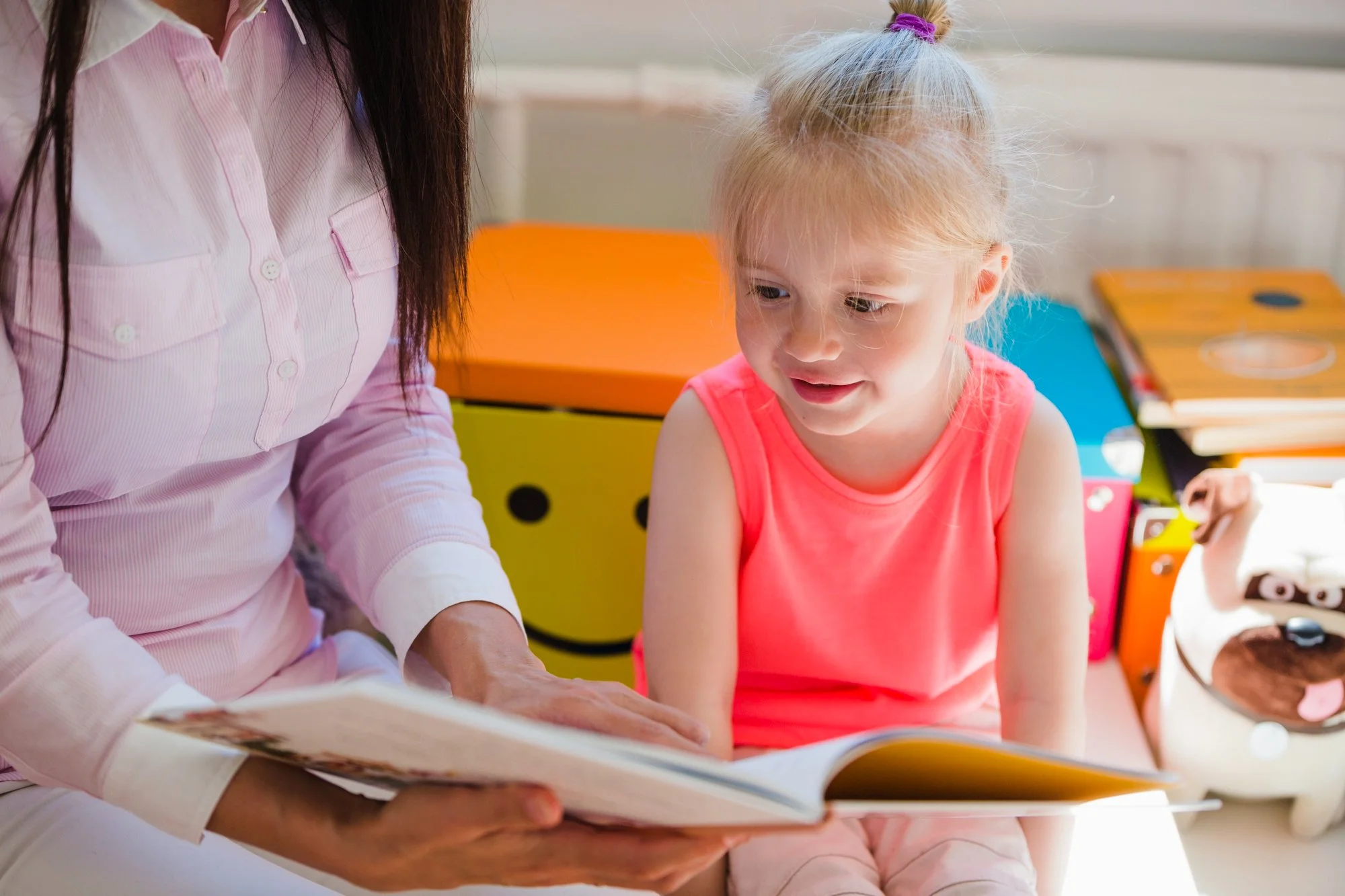 A young child smiling and engaged while reading a book with a parent after building confidence sounding out words
