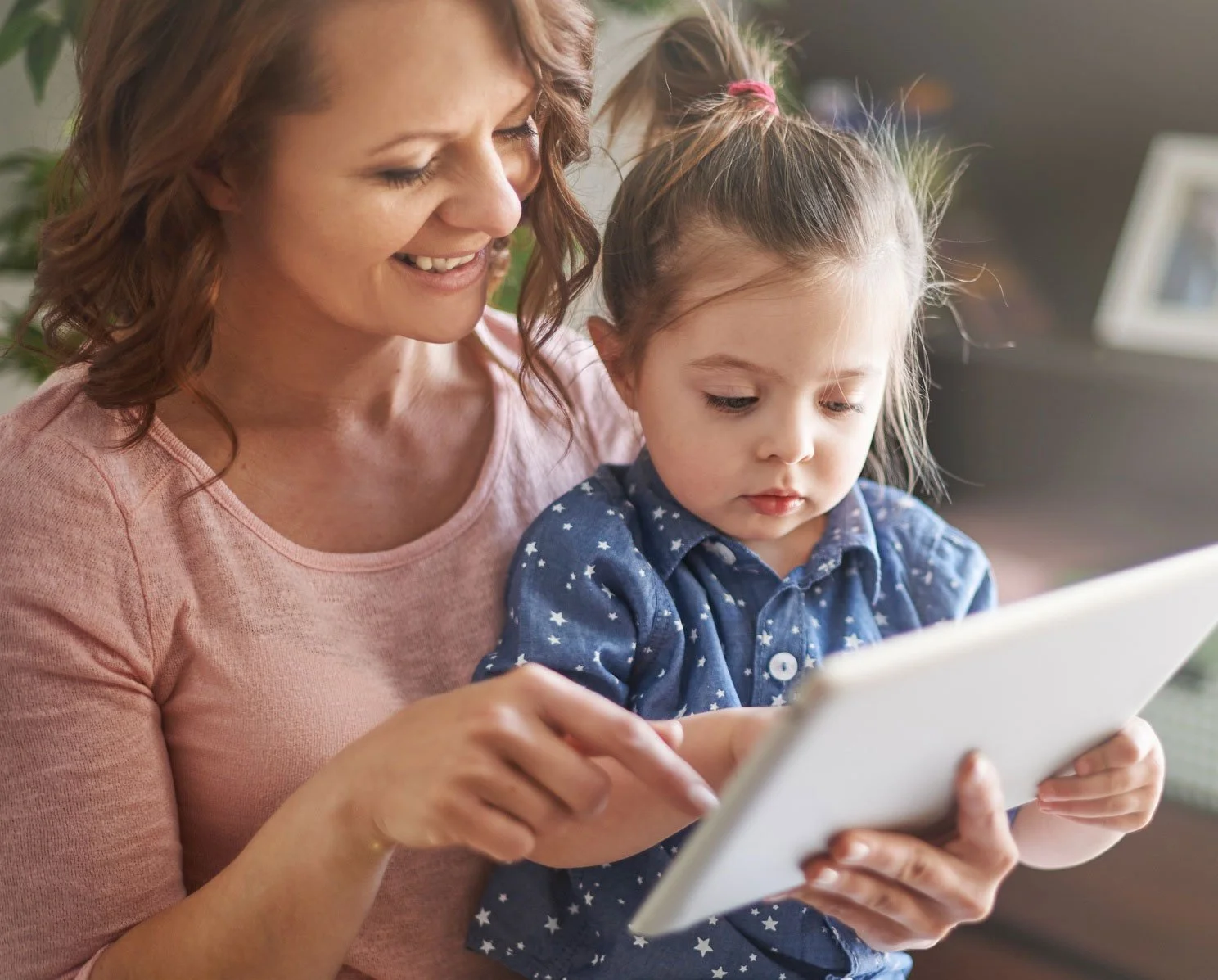 A mother and young child sitting together using a tablet during a parent guided phonics and decoding practice session