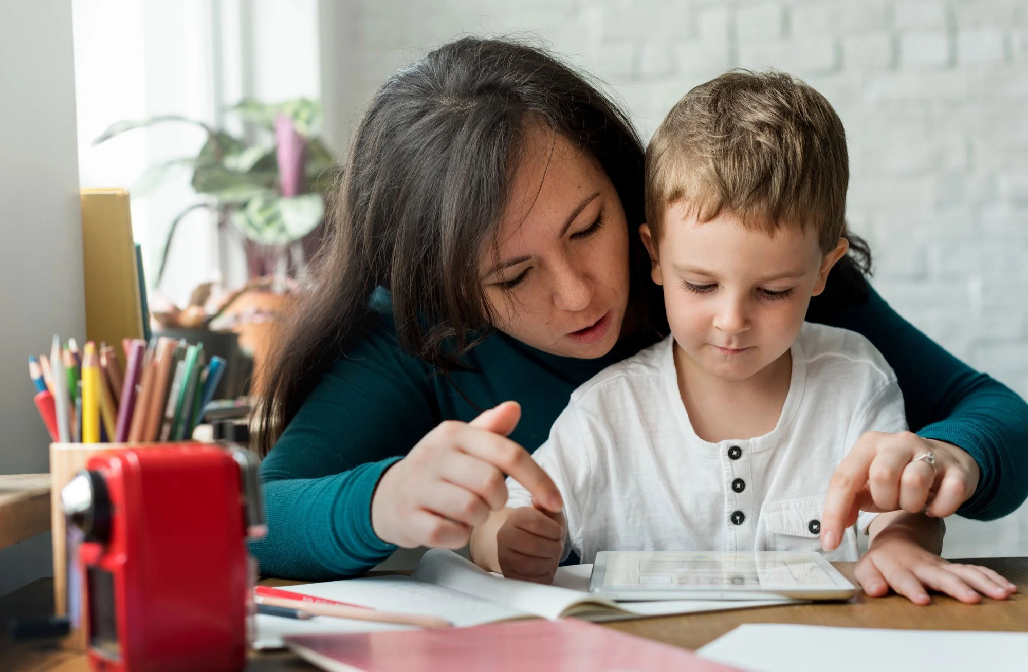 Mother actively involved in her child's reading practice on a tablet