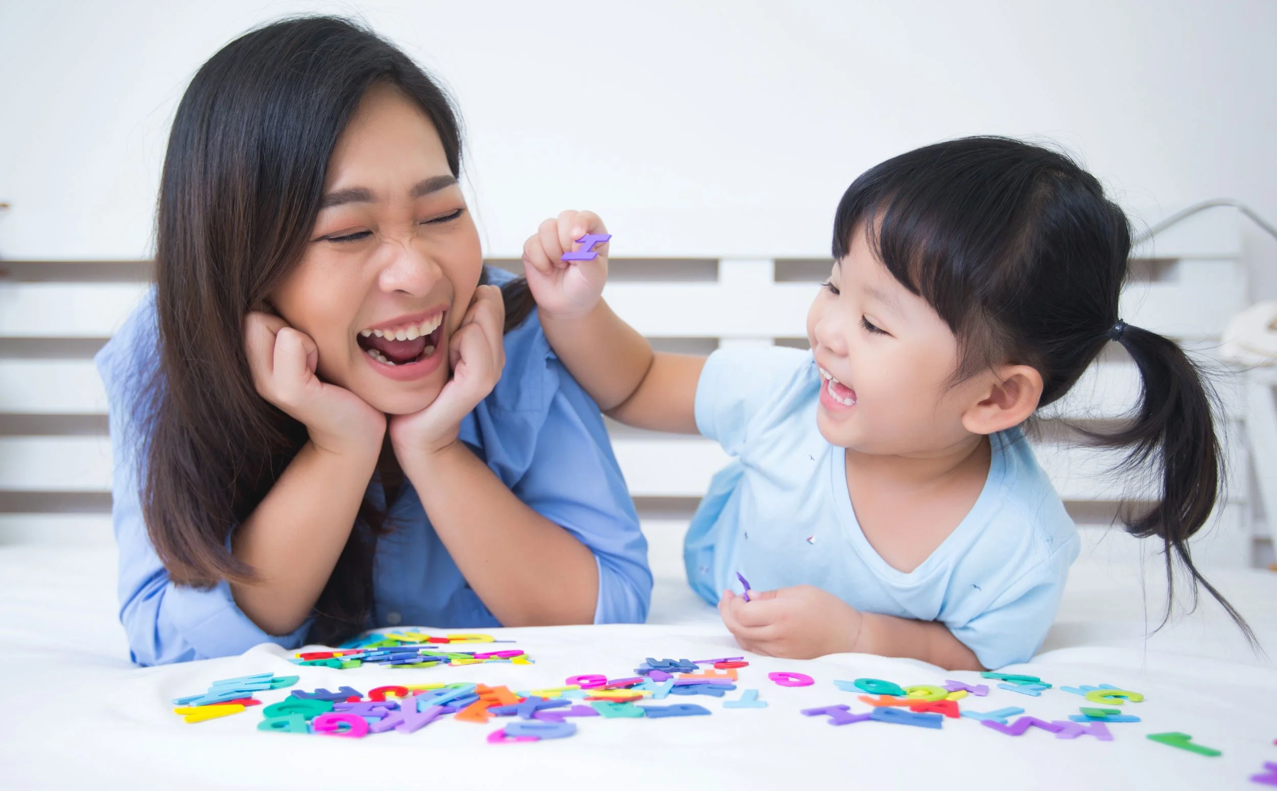 Parent and child racing to build words with wooden letters during a phonics game
