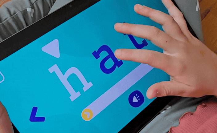 A child using Phonics Factory on a tablet tapping letters to hear their sounds then sliding to say them aloud and blend them into a word before kindergarten
