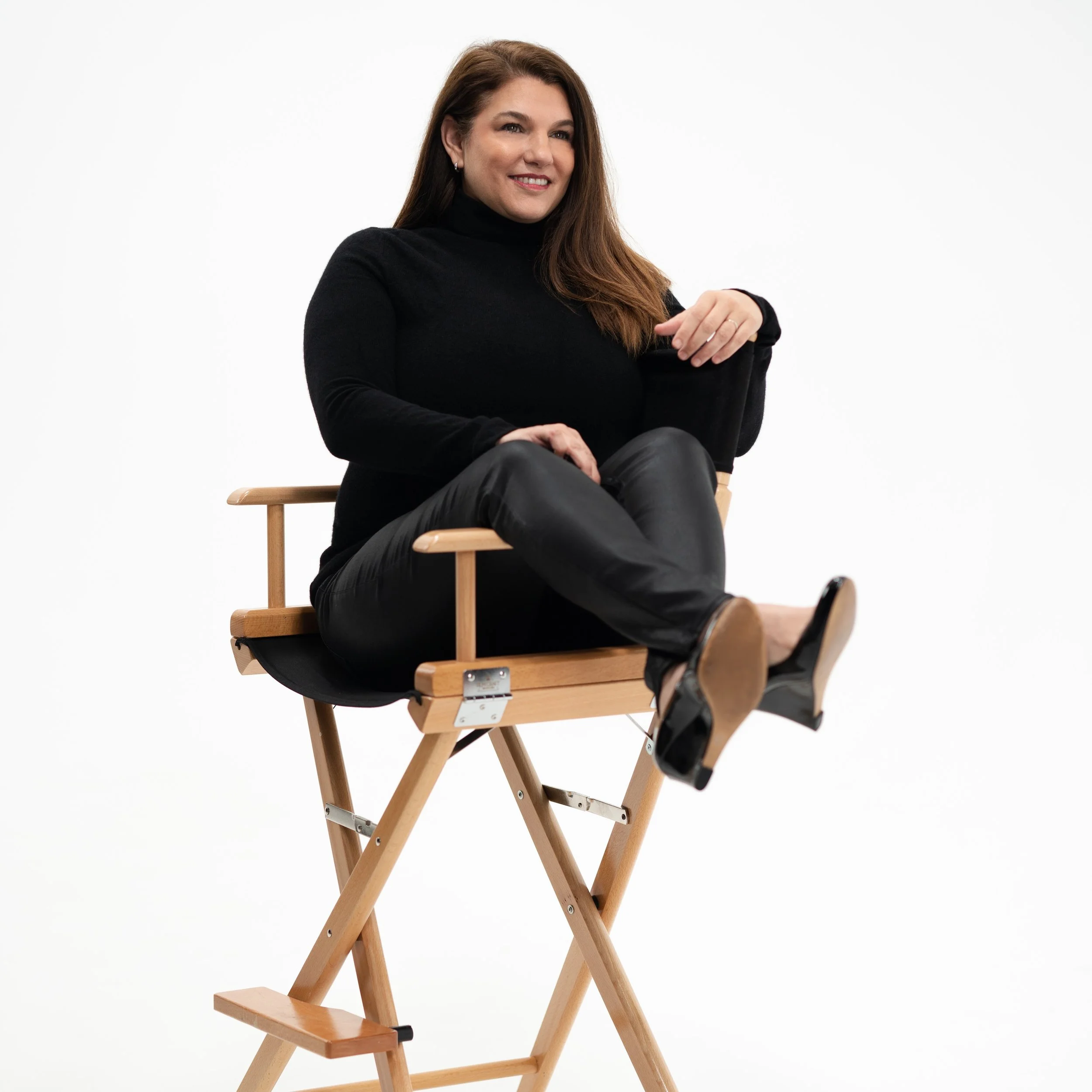 Lynne Arciero, owner of REV Studios, sitting in a directors chair