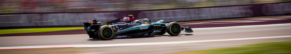 A black Formula 1 race car speeding on a racetrack with a blurred background.
