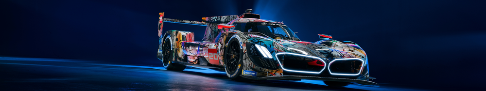 A racing car with a colorful, abstract design, illuminated headlights, and racing decals, positioned on a dark, reflective surface.