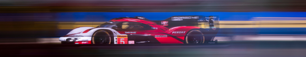 A race car speeding on a track, with motion blur in the background.