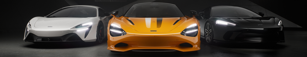 Three luxury sports cars parked side by side in a dark setting, featuring a white, orange, and black car from front view.