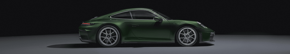Side view of a shiny green sports coupe car on a plain gray surface with a black background.