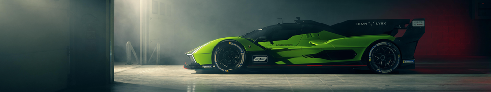 Green and black racing car inside a garage with fog or smoke and red wall in background.