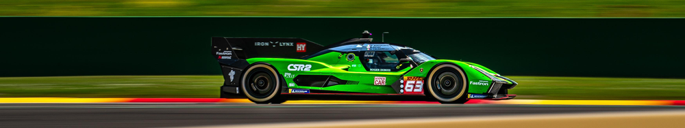 A green and black race car speeding on a racetrack.