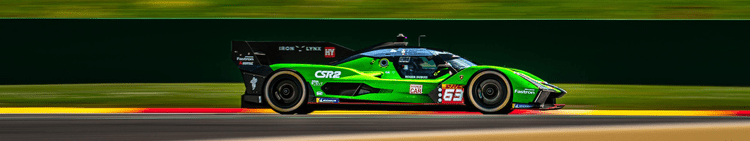 A green and black race car speeding on a racetrack.