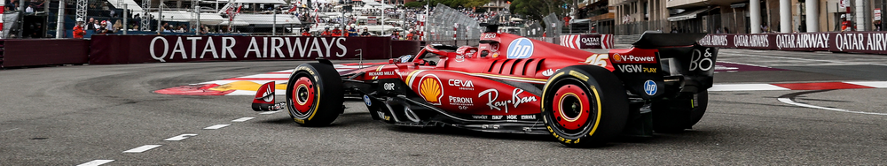 A red Formula 1 race car on a city street circuit during a race, with barriers and Qatar Airways branding in the background.
