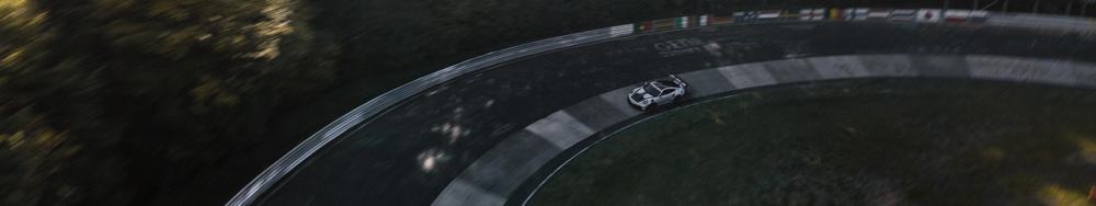 A white sports car driving on a winding mountain road with guardrails, surrounded by trees.