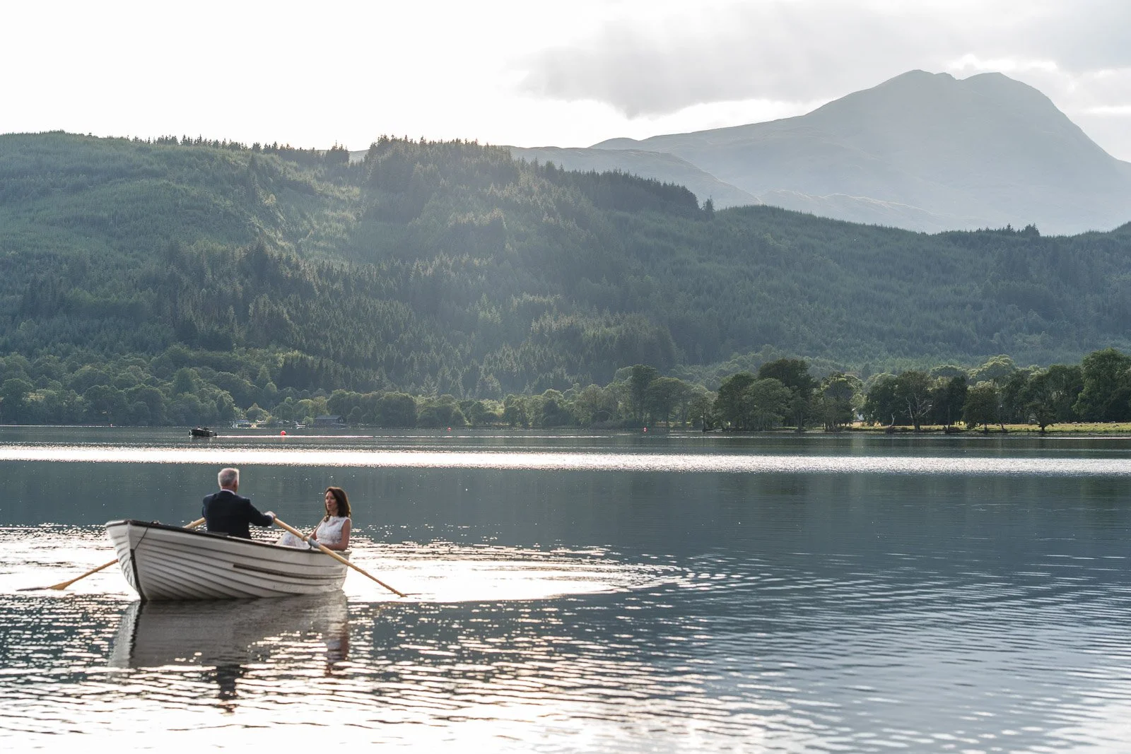 Newly married couple on a boat with Ben Lomond behind them at a great Scottish wedding in the Trossachs
