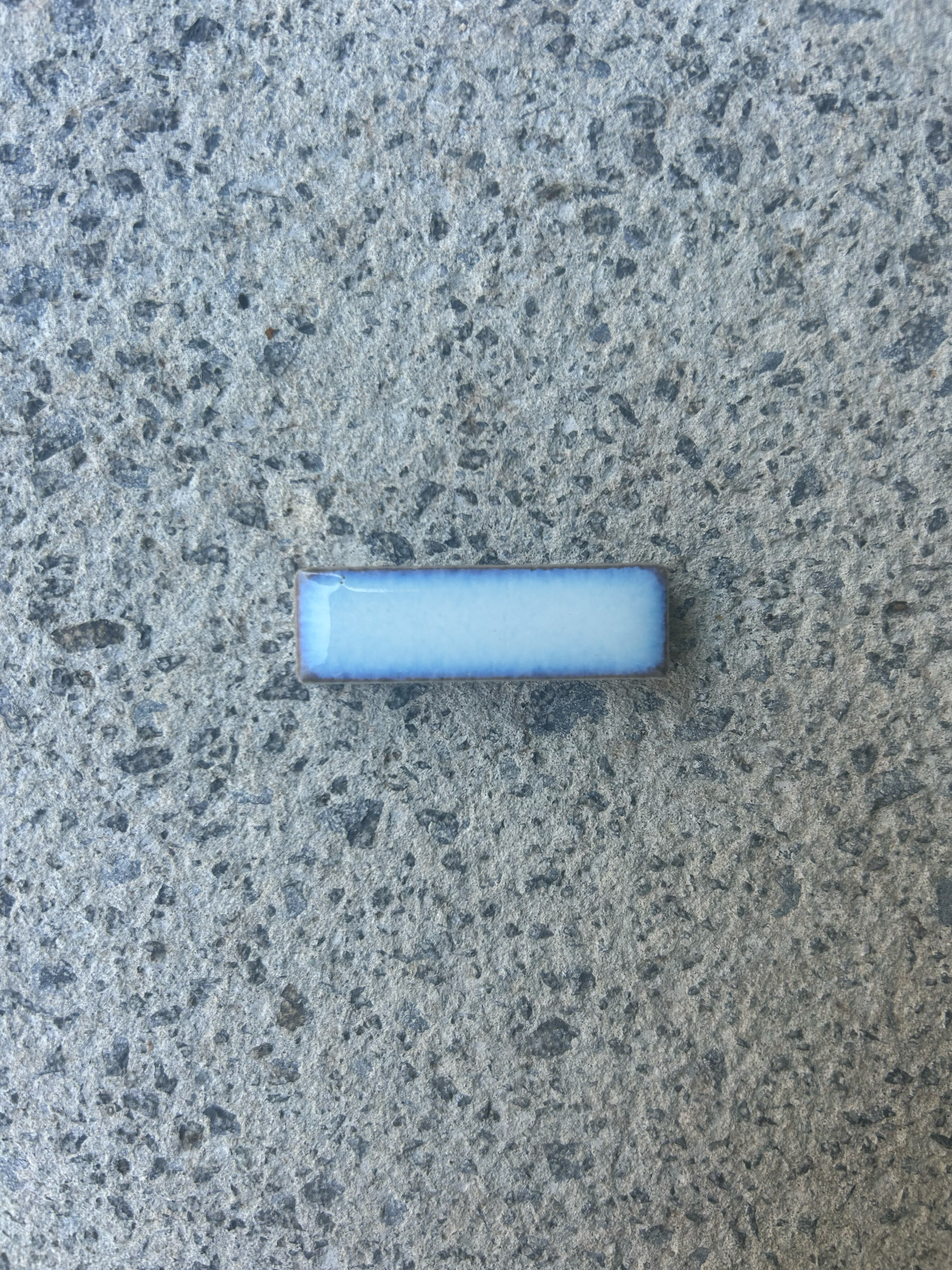A small rectangular object with a blue top and white face on a rough concrete surface. Existing pool refurbishment Built by ESC outdoor living swimming pool builders. Auckland. skilled builders