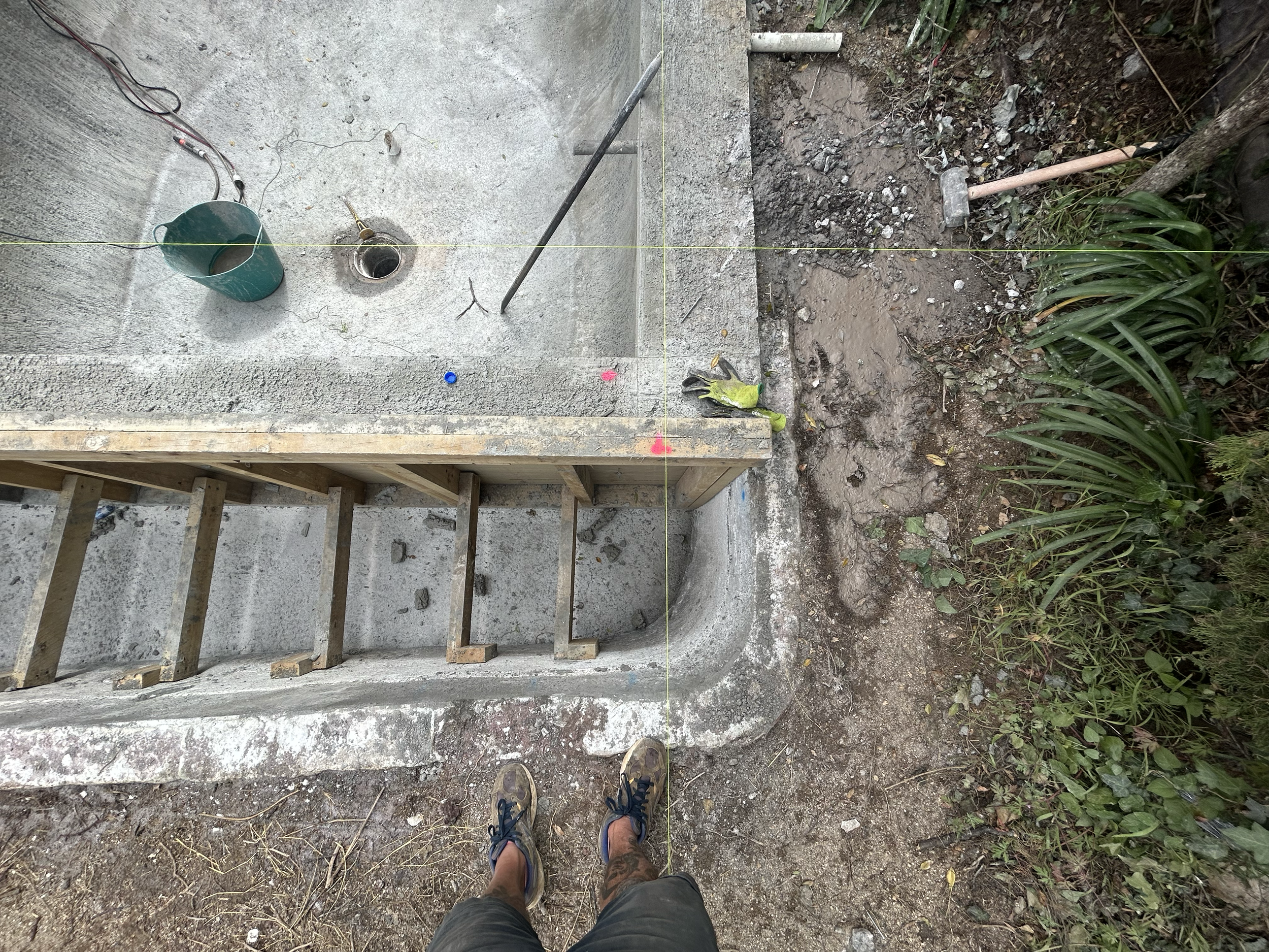 Photograph of a pool construction site showing a person standing on dirt and concrete, Existing pool refurbishment Built by ESC outdoor