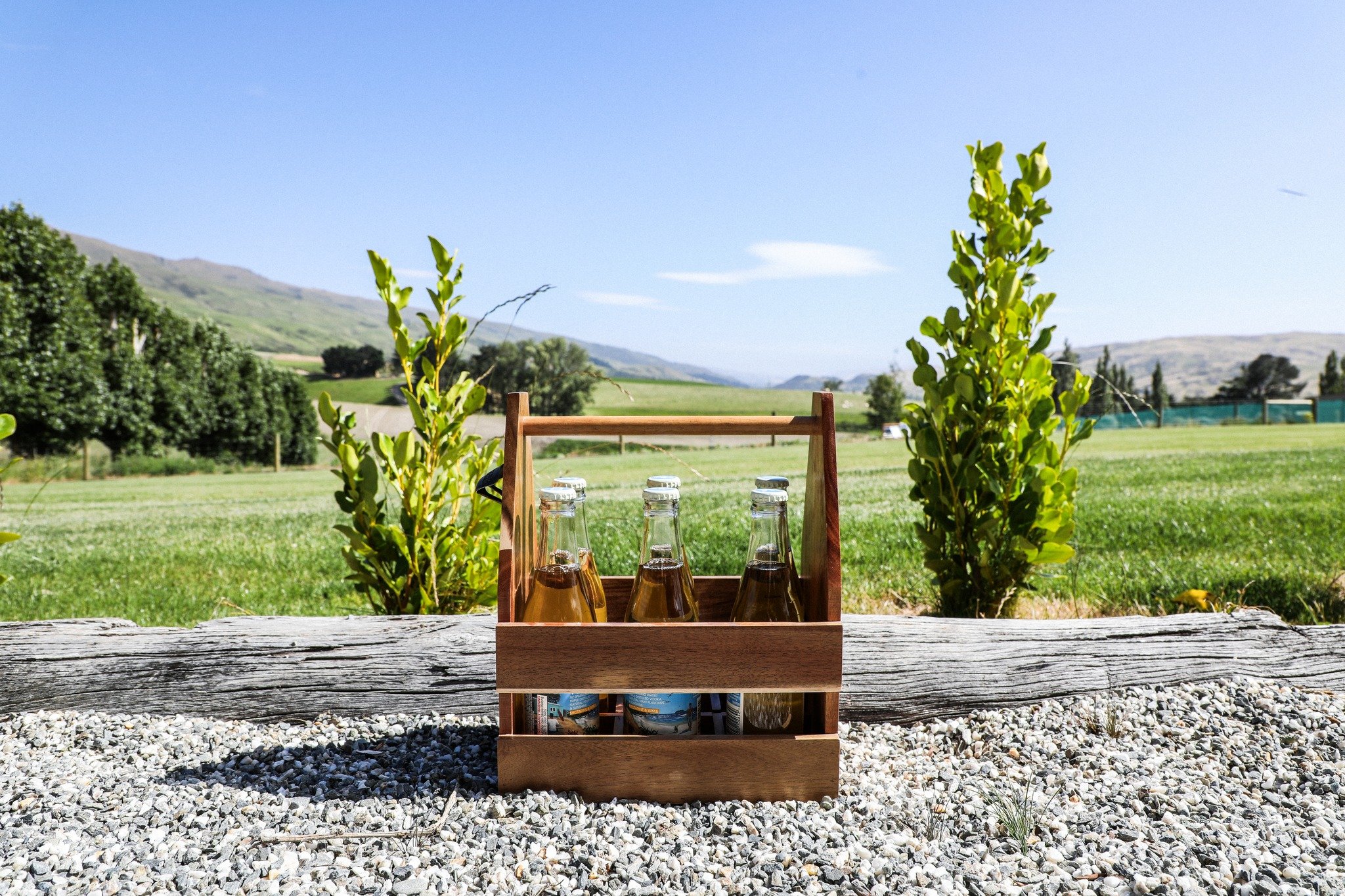 The Keepsake Beverage Caddy, crafted from acacia wood, is a distinctive and versatile gift suitable for outdoor gatherings, hospitality, and picnics. Complete with a convenient built-in brass bottle opener, it accommodates up to six cans or small bot