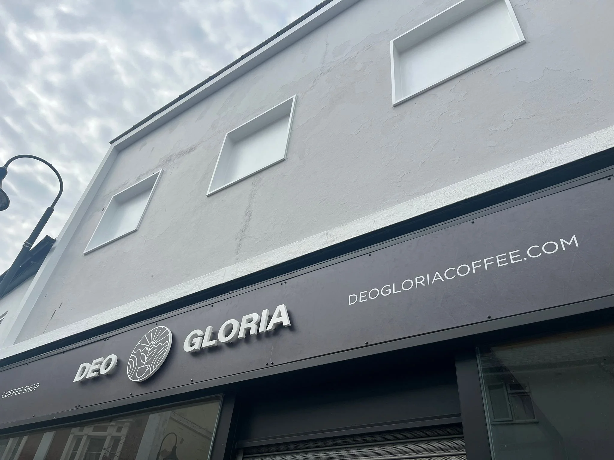 The outside of Deo Gloria coffee shop looking up at the cloudy sky