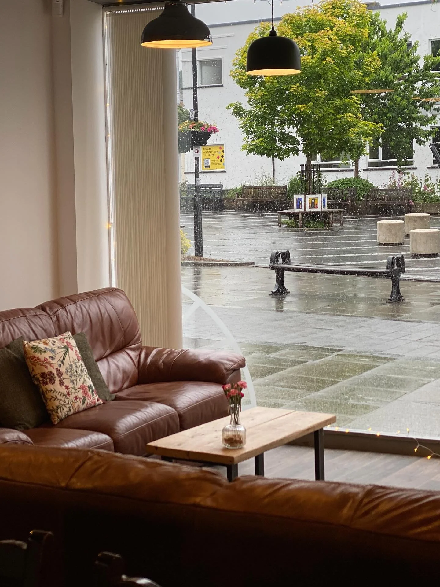 The warm comfortable Deo Gloria sofas sit in the foreground while the big glass windows behind then reveal the rain outside