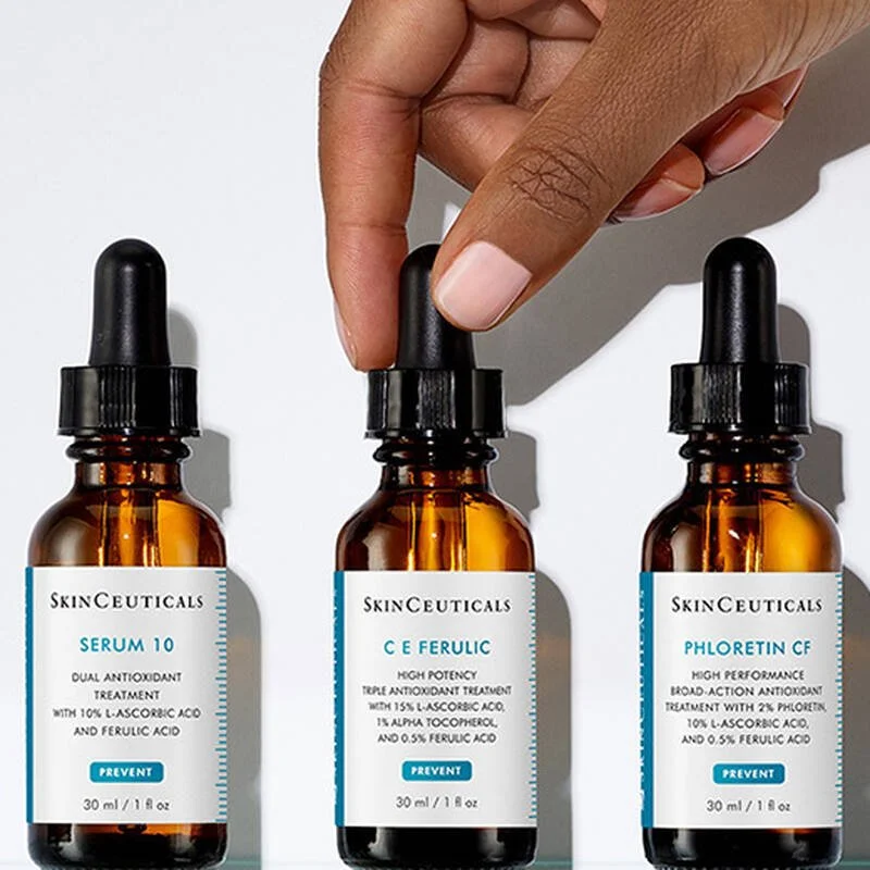 Three amber glass dropper bottles with black droppers, labeled 'SkinCeuticals.' The left one is labeled 'Serum 10,' the middle one 'C E Ferulic,' and the right one 'Phloretin CF.'