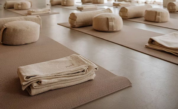 Yoga mats and folded towels arranged on the floor in a tranquil, well-lit studio.