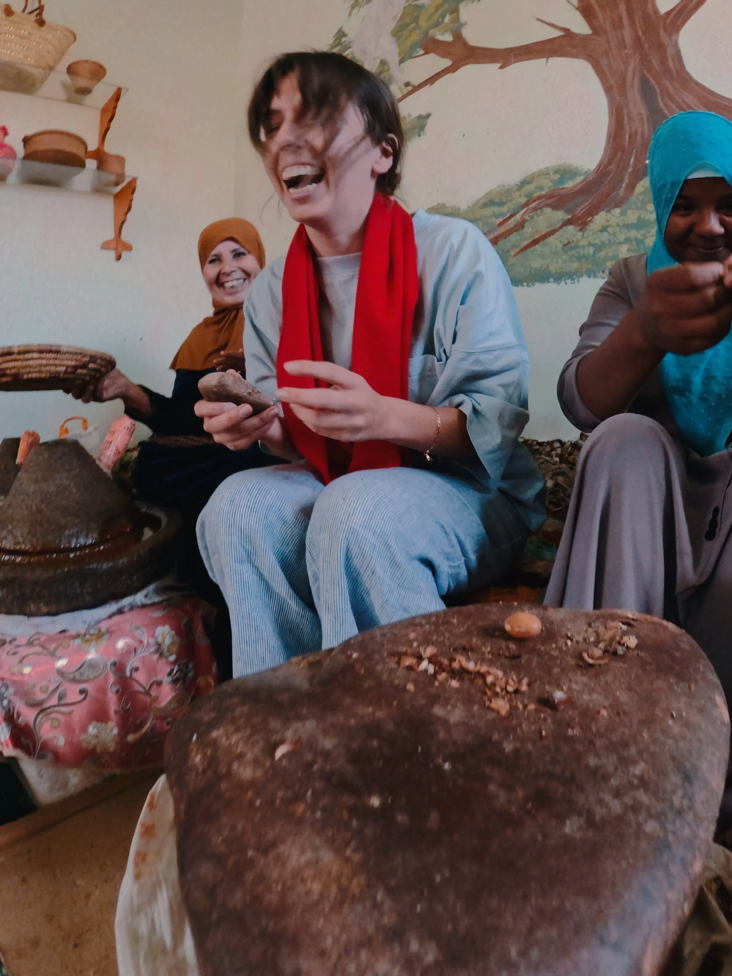 Women in traditional attire sitting together, enjoying a meal with the focus on a large piece of bread in the foreground.