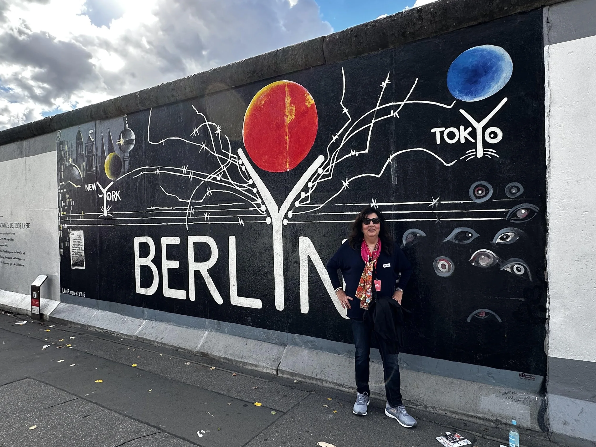 Maria standing beside a Berlin Wall mural at the East Side Gallery.