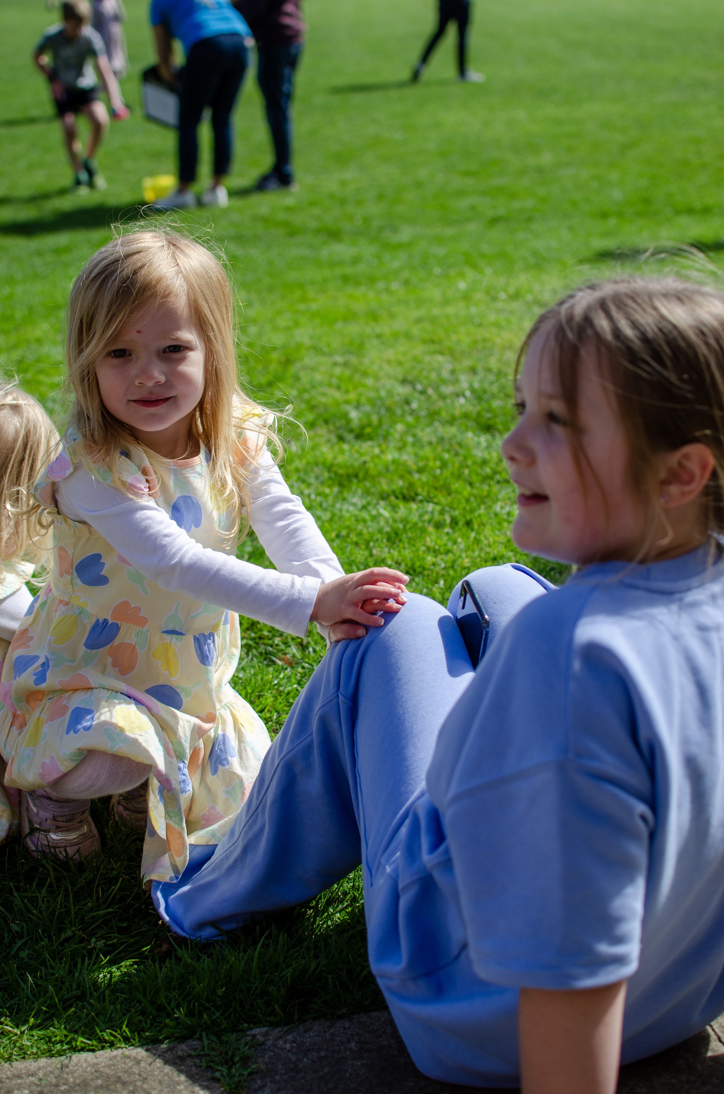 2 children hanging out outside on the grass. 