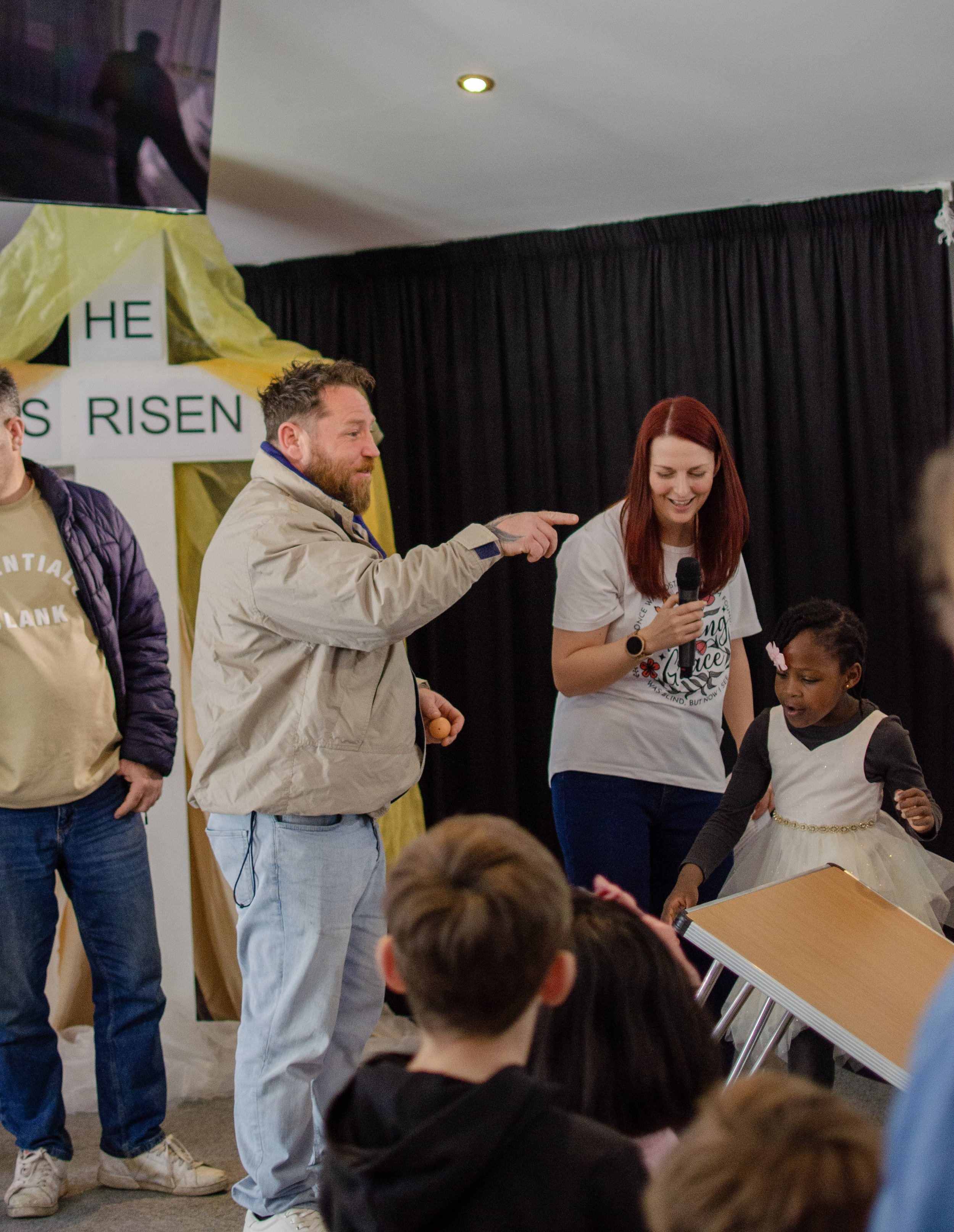 A man woman and child laughing at an egg rolling competition