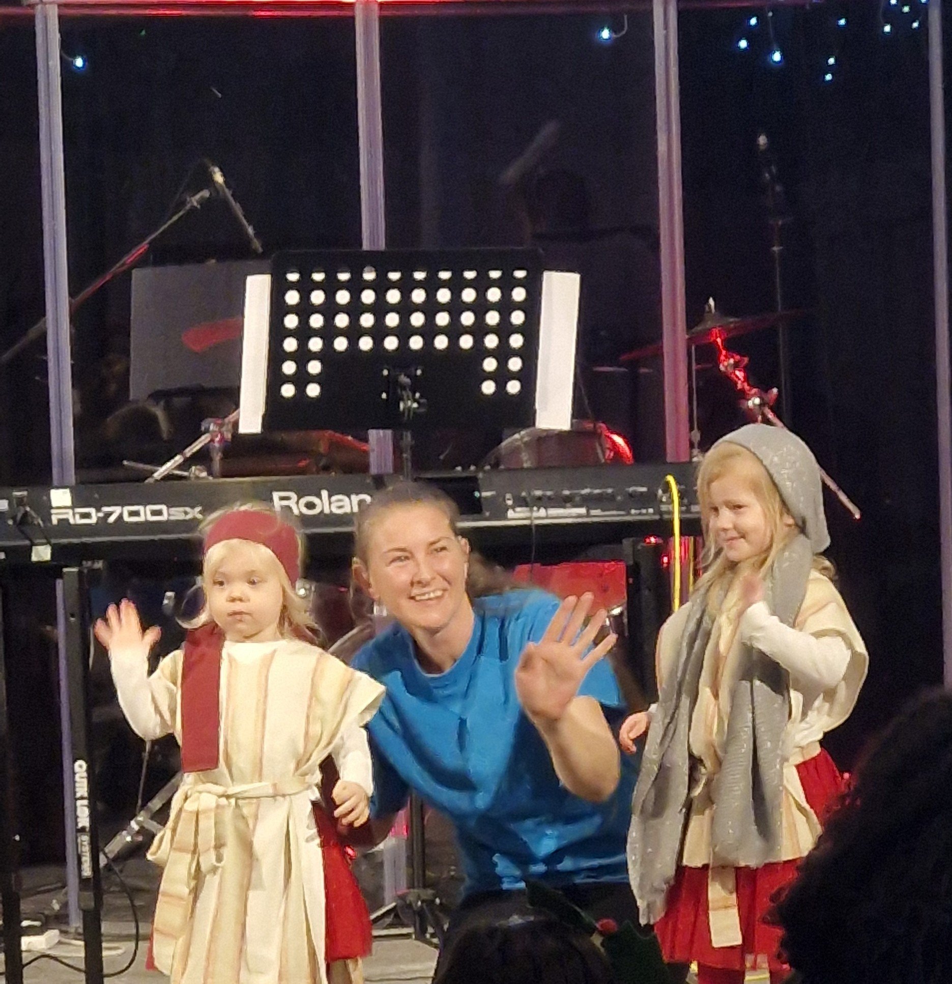 2 little girls and a leader dressed for a play and waving at the congregation
