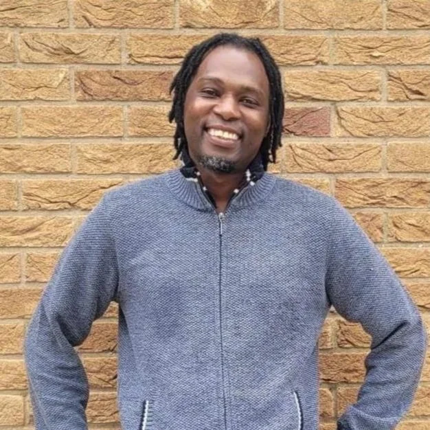 A smiling man in a grey top