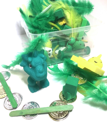 Sensory bin with green feathers, dinosaurs, and toys for St. Patrick's Day speech therapy
