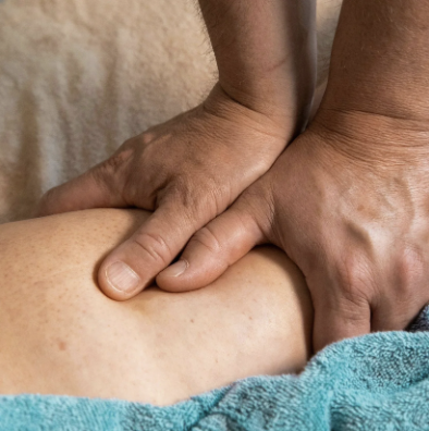 Male massage therapist performing deep tissue massage technique on client's back in Los Angeles