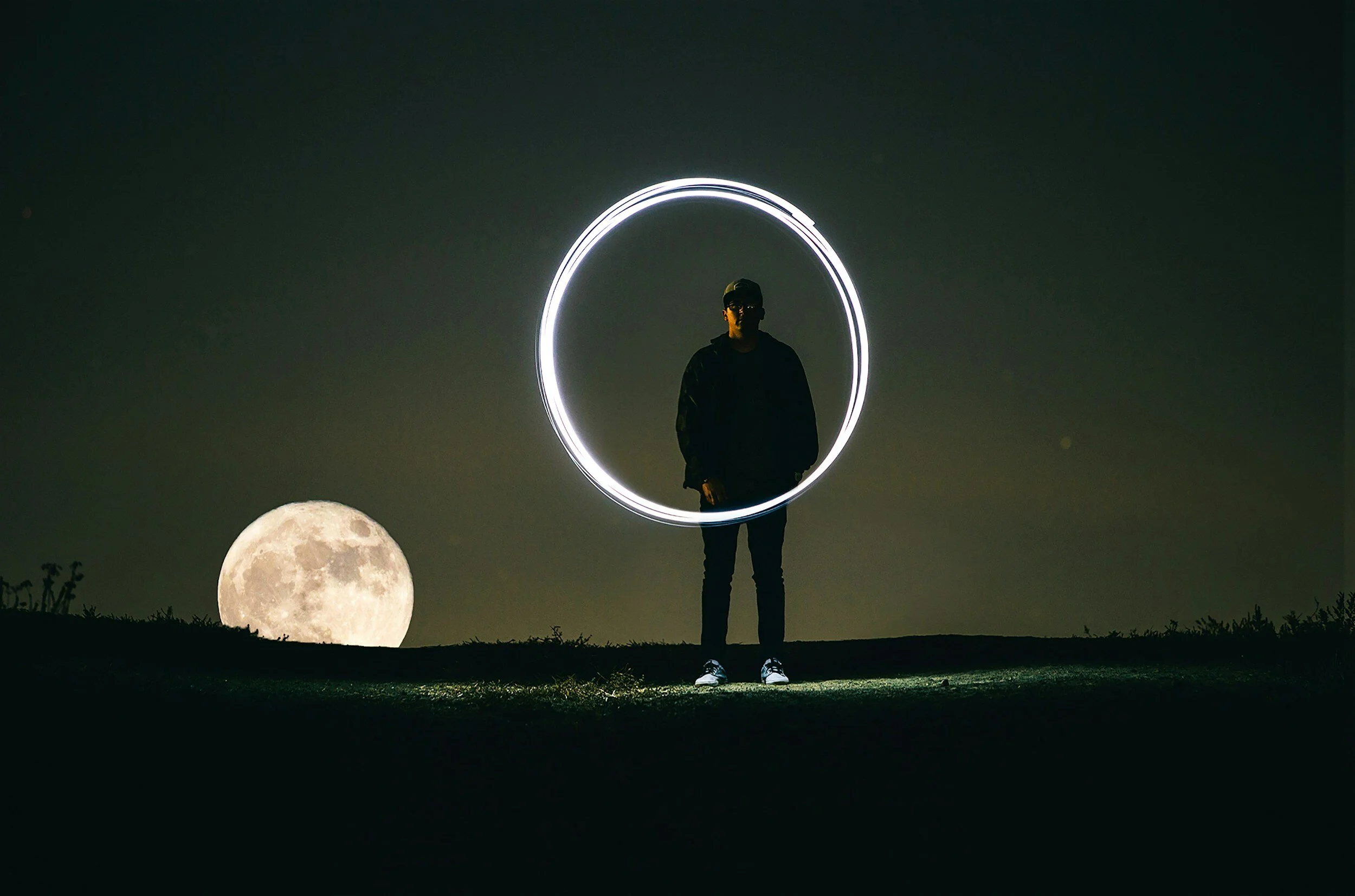 Silhouette of a person with a light circle, full moon in the background