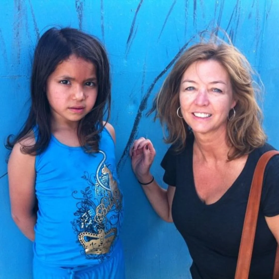 Host Deborah Rohan standing next to Palestinian refugee child
